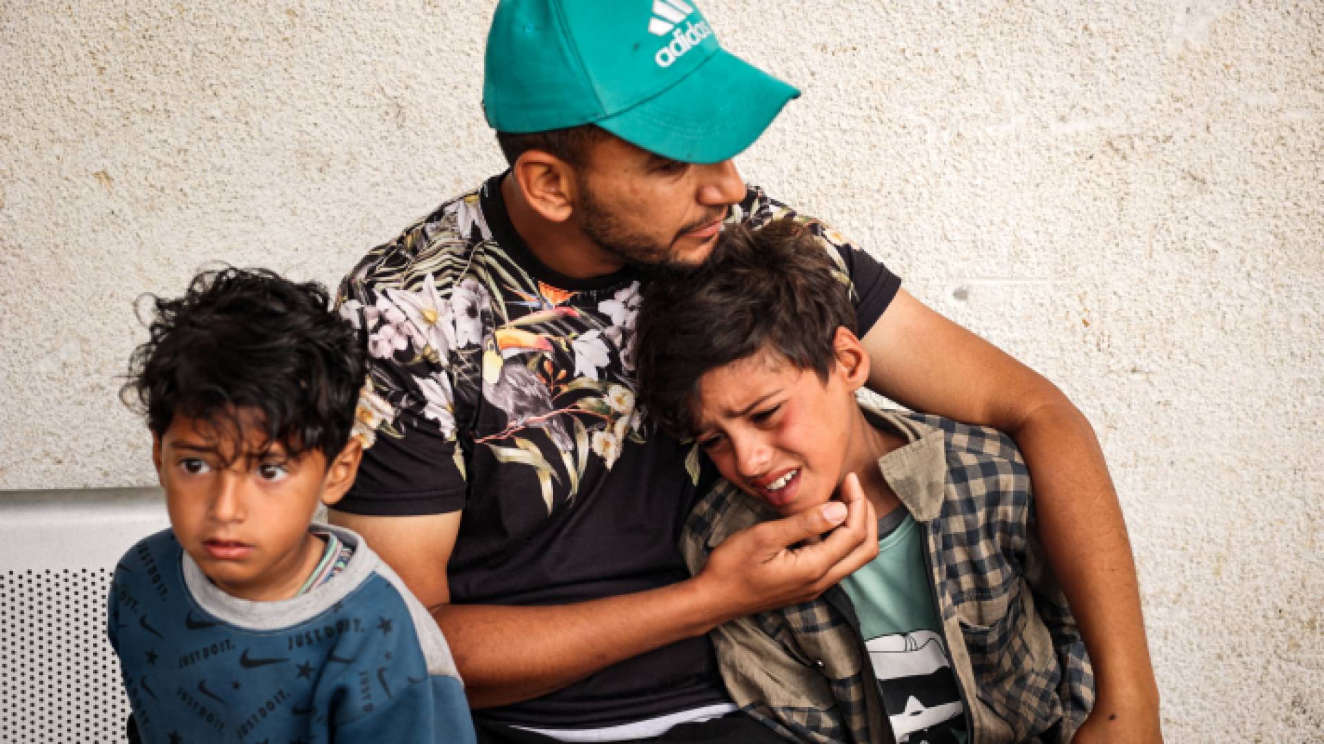 فلسطيني يحتضن أبناءه بعد استشهاد والدتهم في قطاع غزة