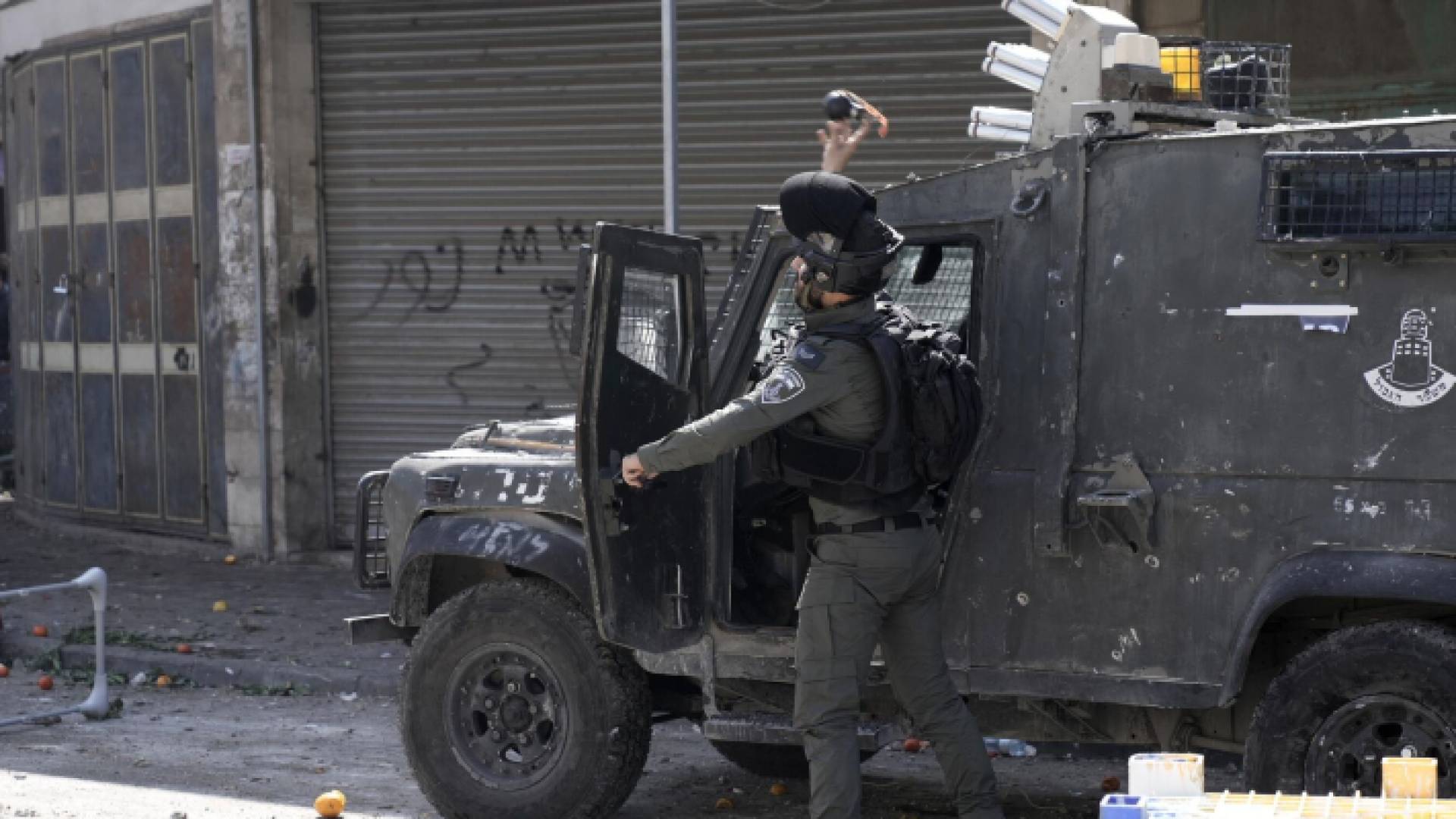 جندي من جيش الاحتلال يلقي قنبلة غاز صوب الفلسطينيين