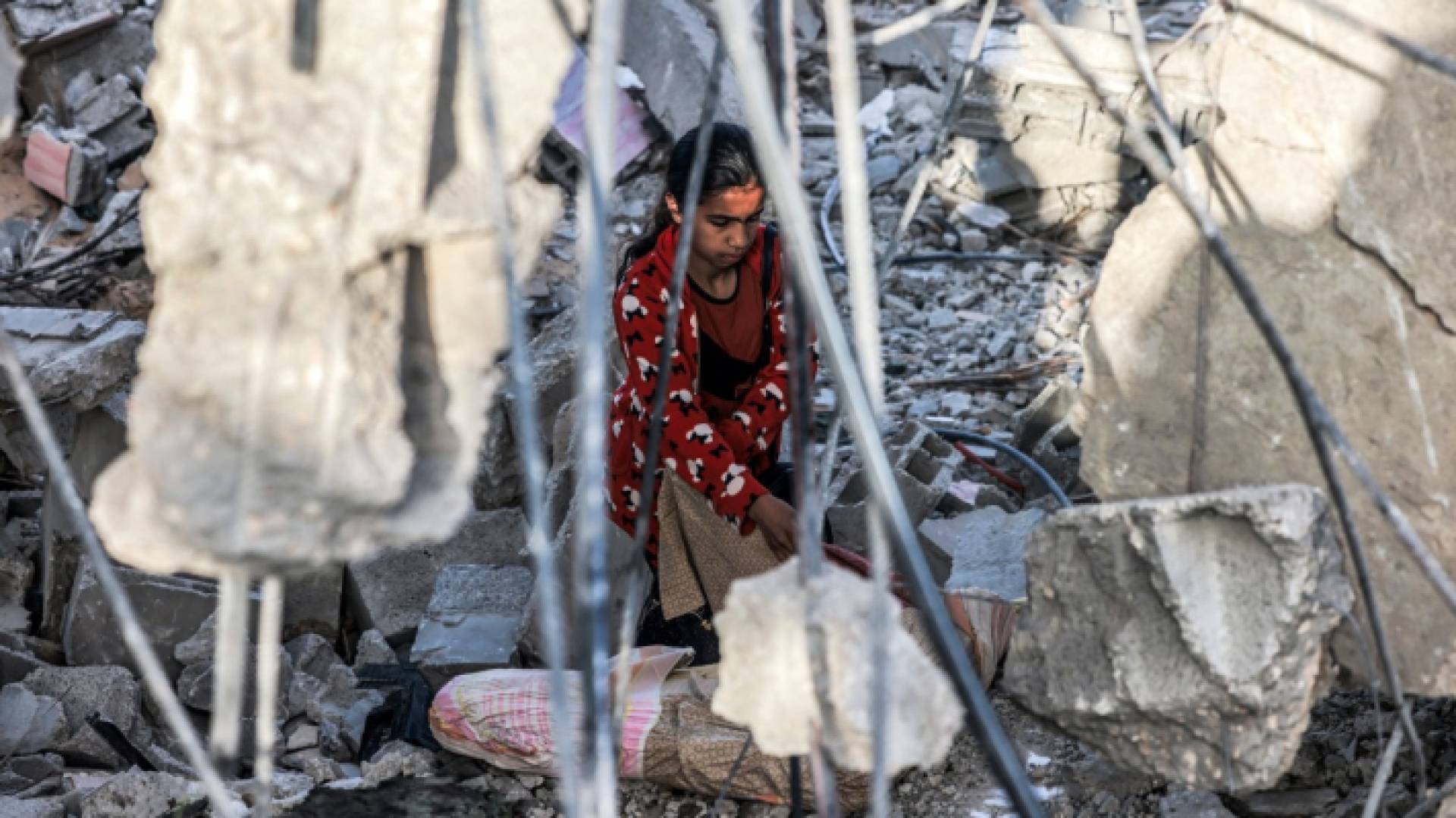 فلسطينية تجلس تحت سقف منزل ذويها المدمر في غزة