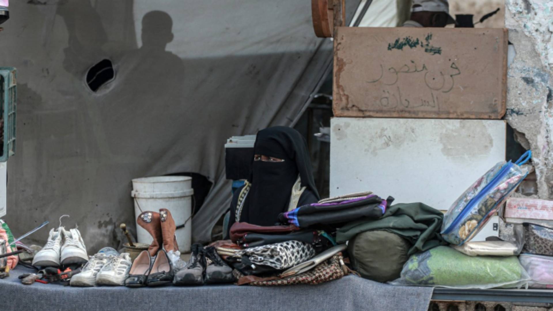 امرأة فلسطينية تبيع أحذية وأشياء أخرى في دير البلح وسط قطاع غزة