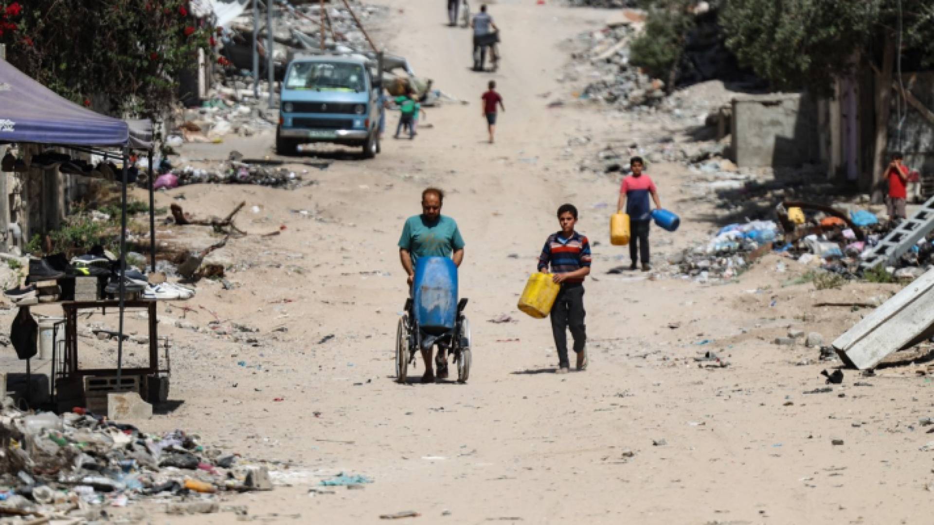 فلسطينيون يحملون قوارير وهم يسيرون نحو نقطة توزيع المياه في مدينة غزة