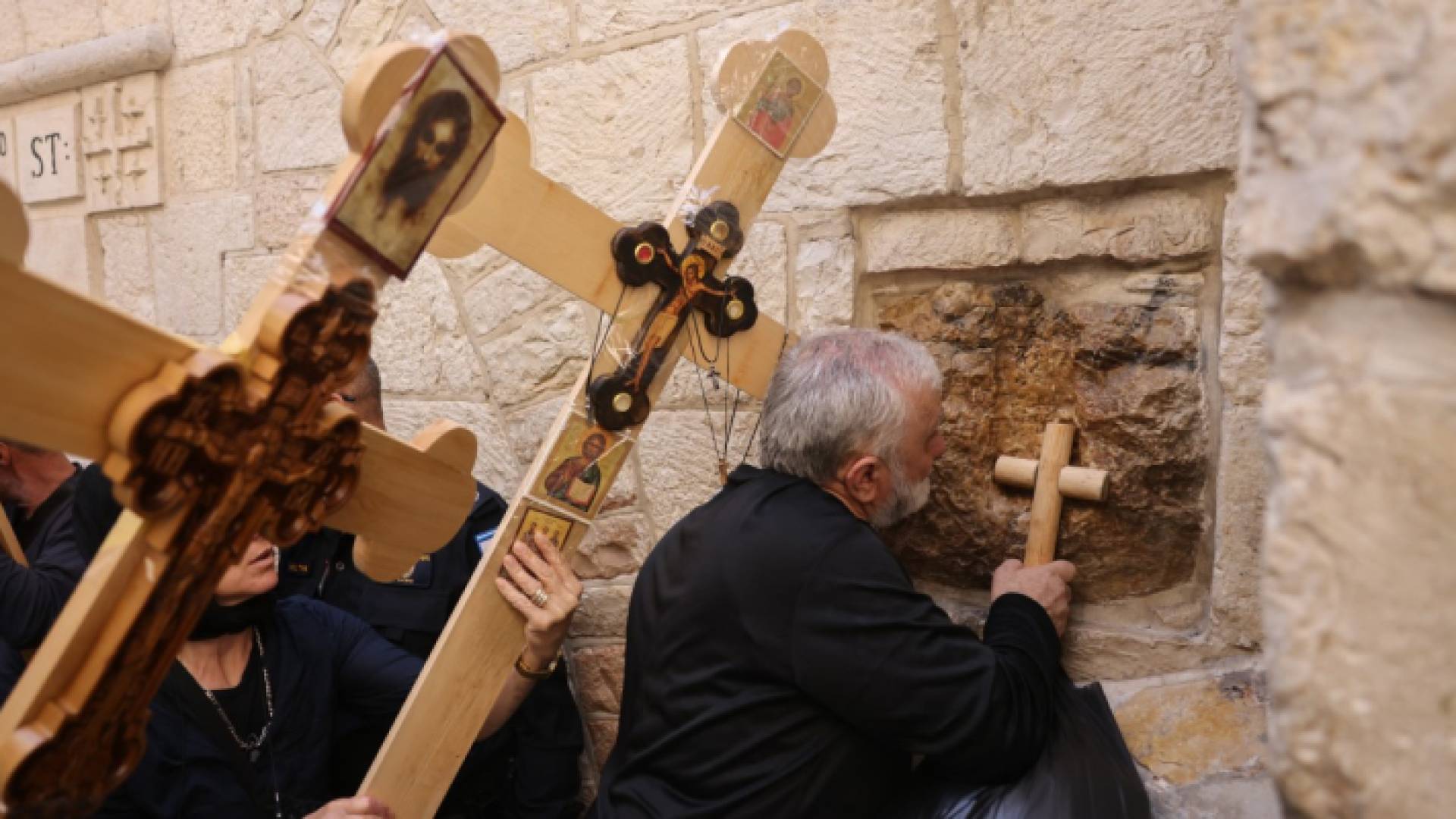 عابد مسيحي أرثوذكسي يلمس محطة على طول طريق الآلام في البلدة القديمة بالقدس بصليب