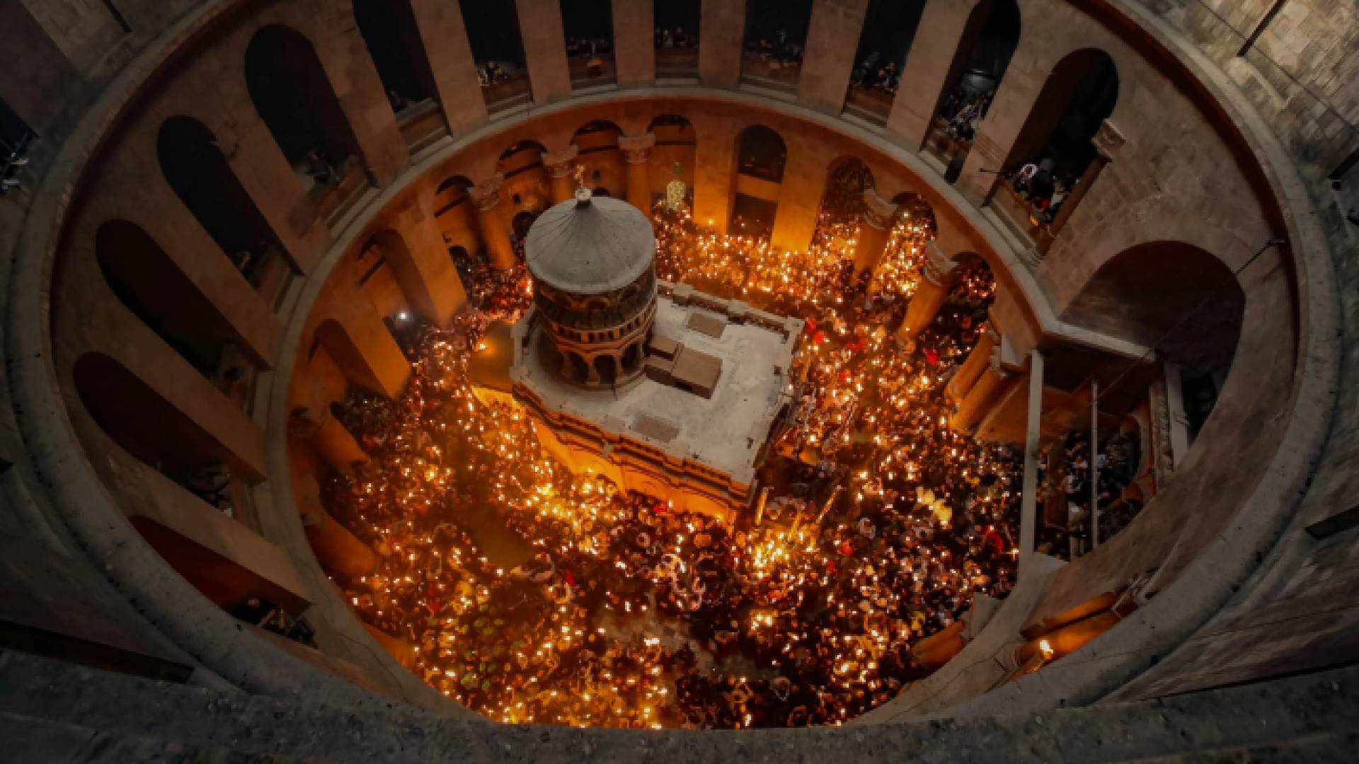 مسيحيون يمررون شعلة مأخوذة من قبر المسيح خلال مراسم إيقاد النار المقدسة حتى تضيء الشموع كنيسة القيامة