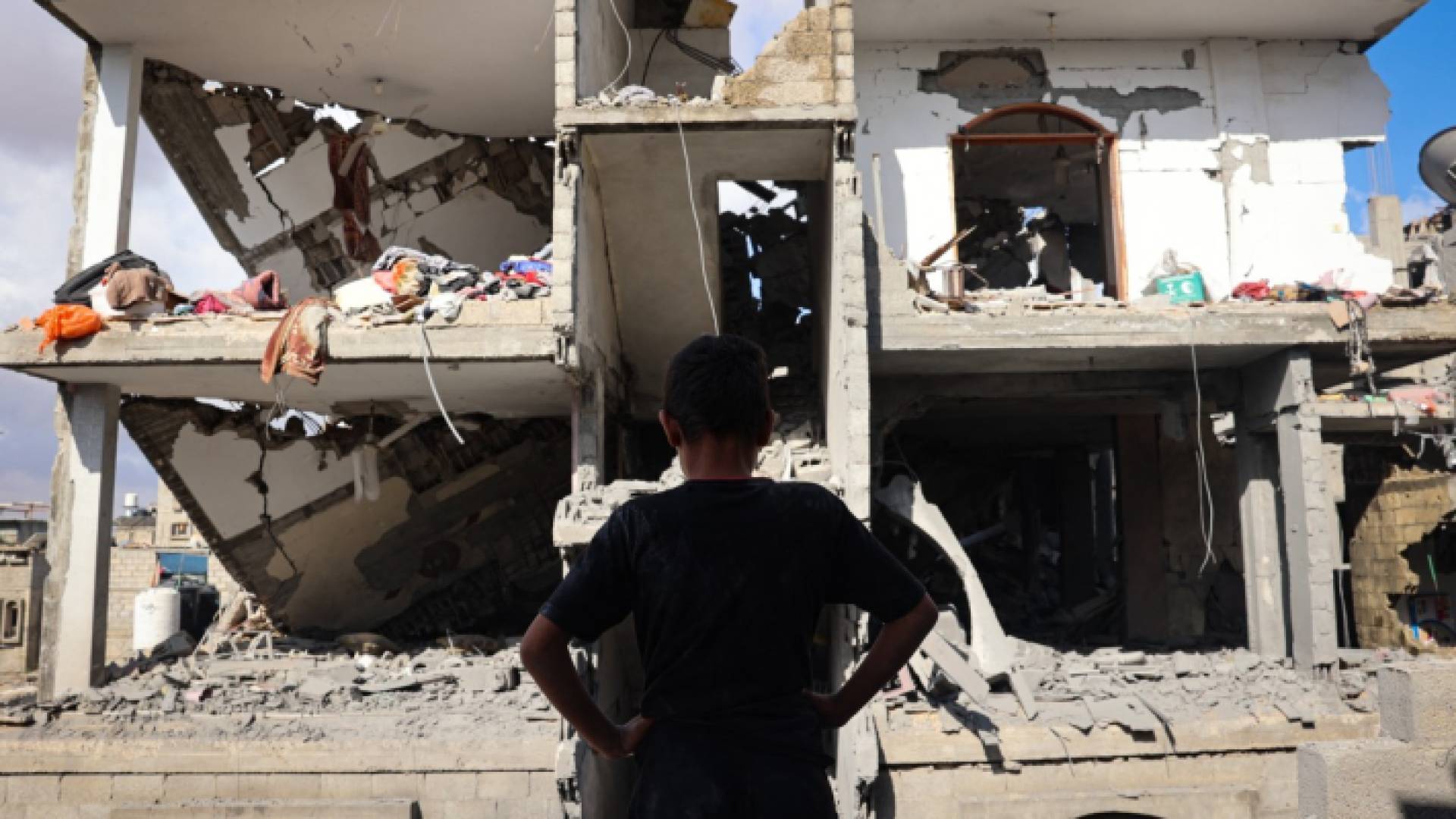 طفل يقف أمام مبنى مدمر بقصف الاحتلال على رفح جنوبي غزة