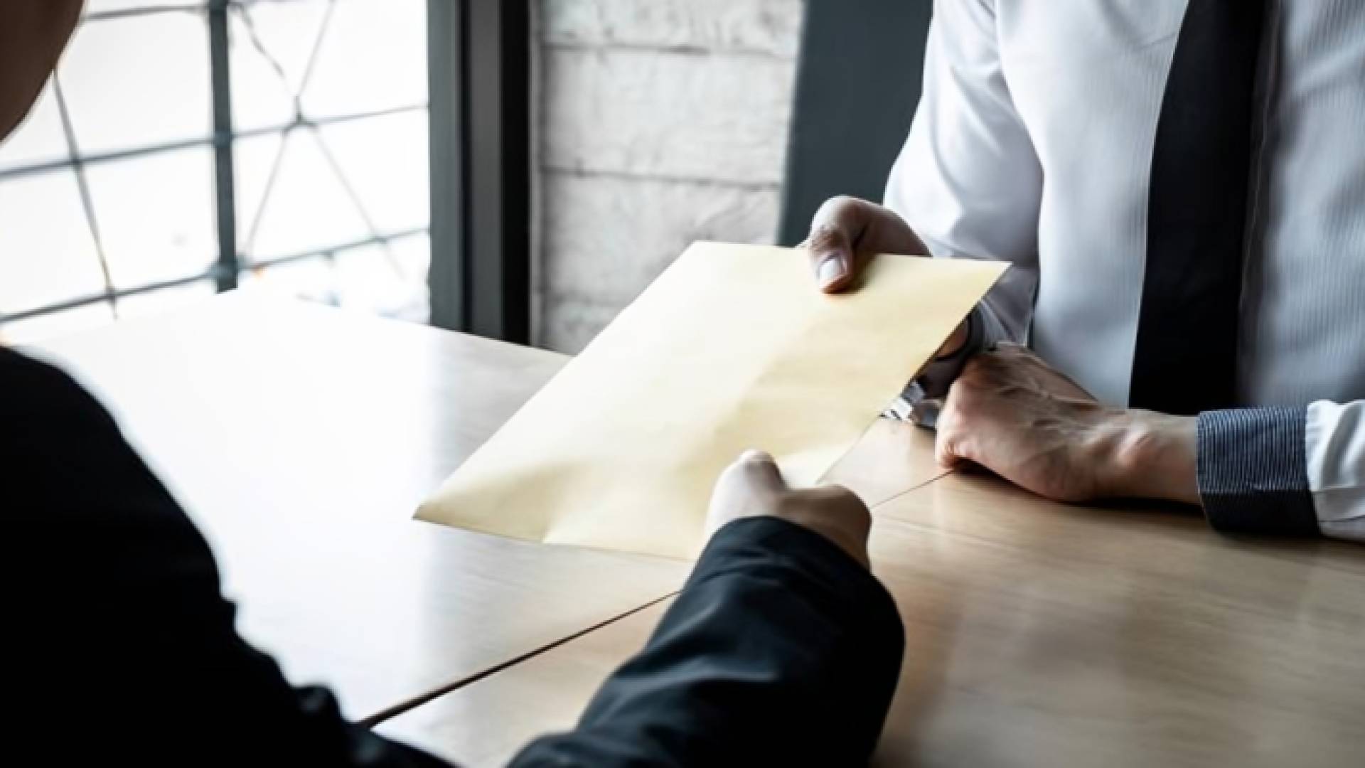 شخص يقدم مغلفا لآخر "تعبيرية"