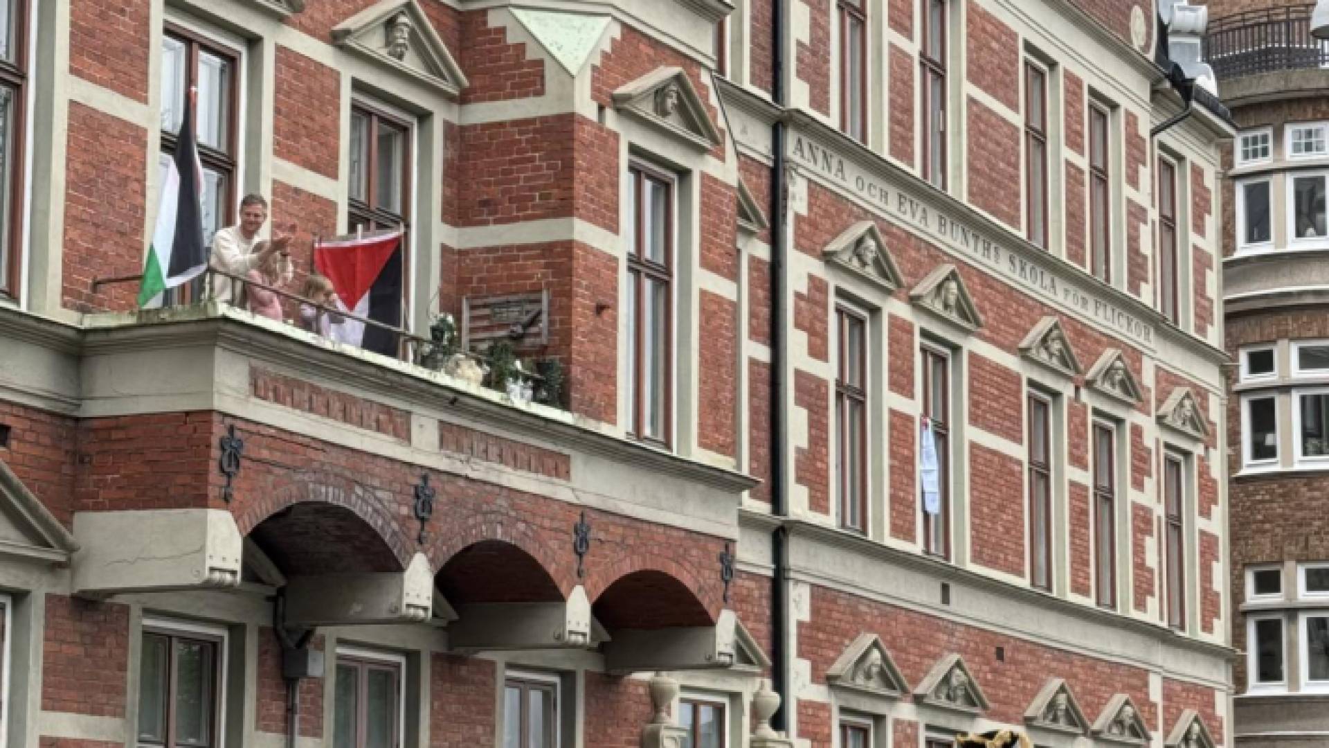 رجل يرفع العلم الفلسطيني من شرفة خلال مسيرة تناصر الفلسطينيين