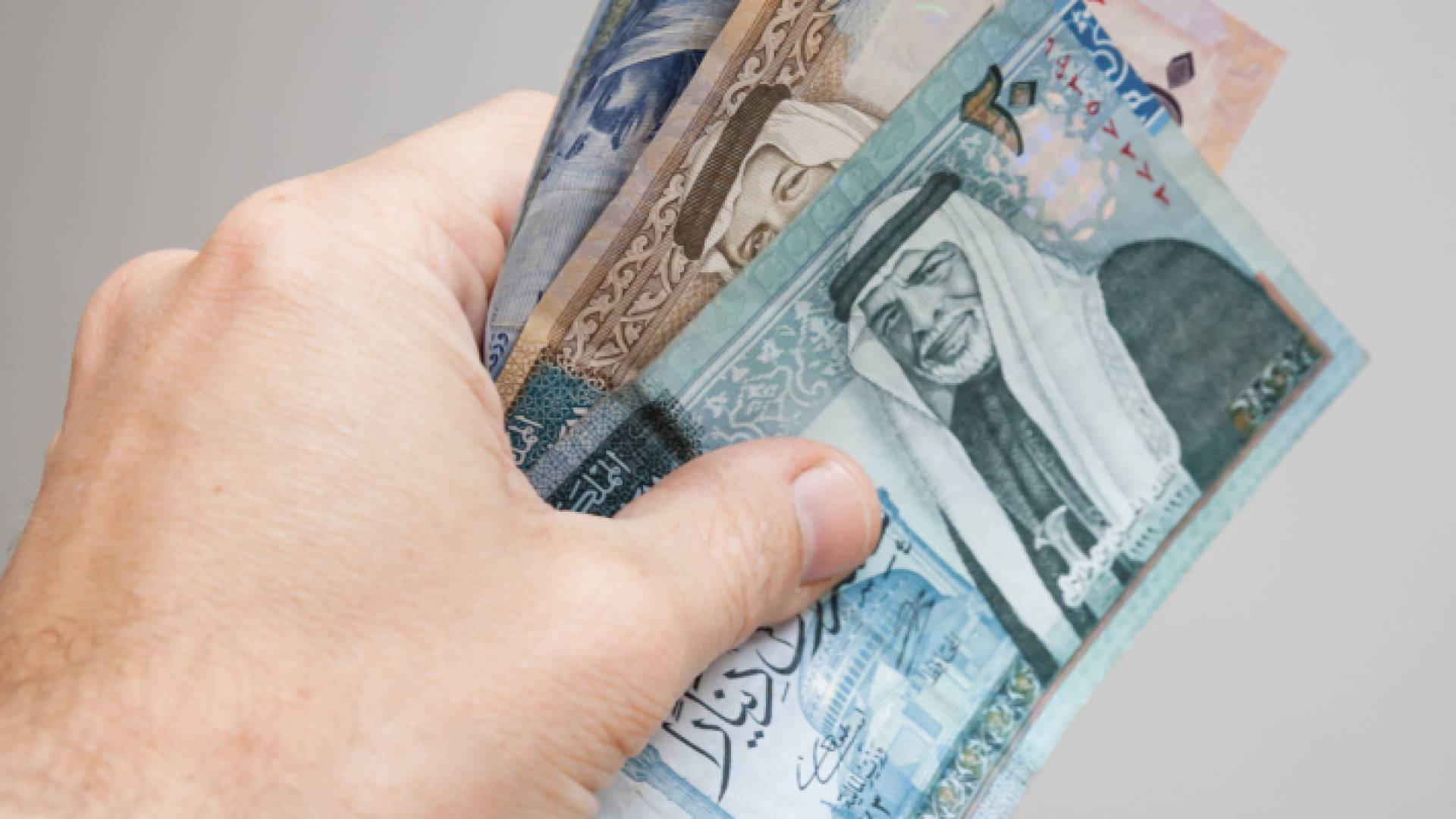 شخص يحمل بيده أوراق نقد أردنية