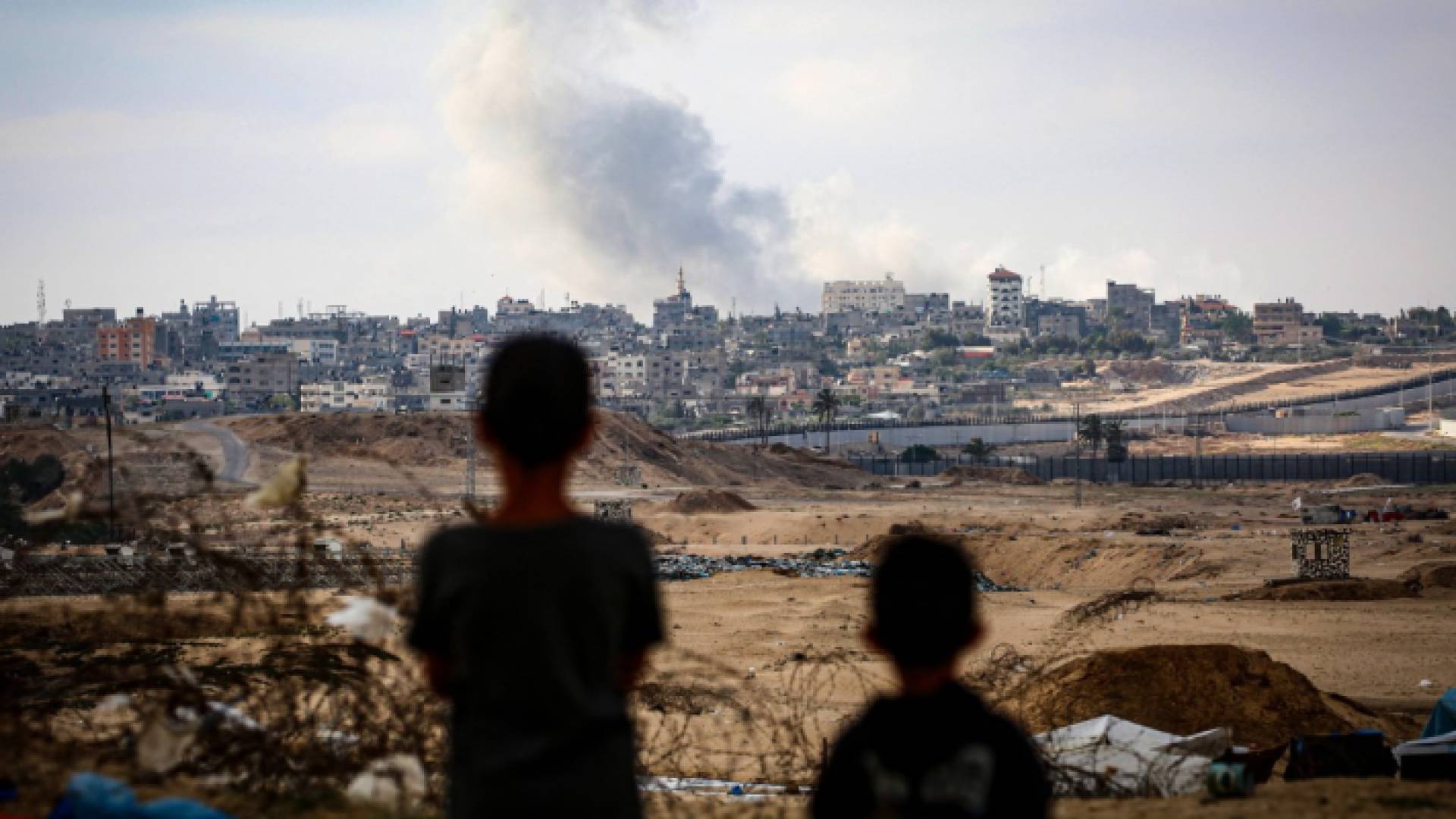 طفلان يشاهدان الدخان المتصاعد عد قصف الاحتلال لأحد المباني في مدينة رفح