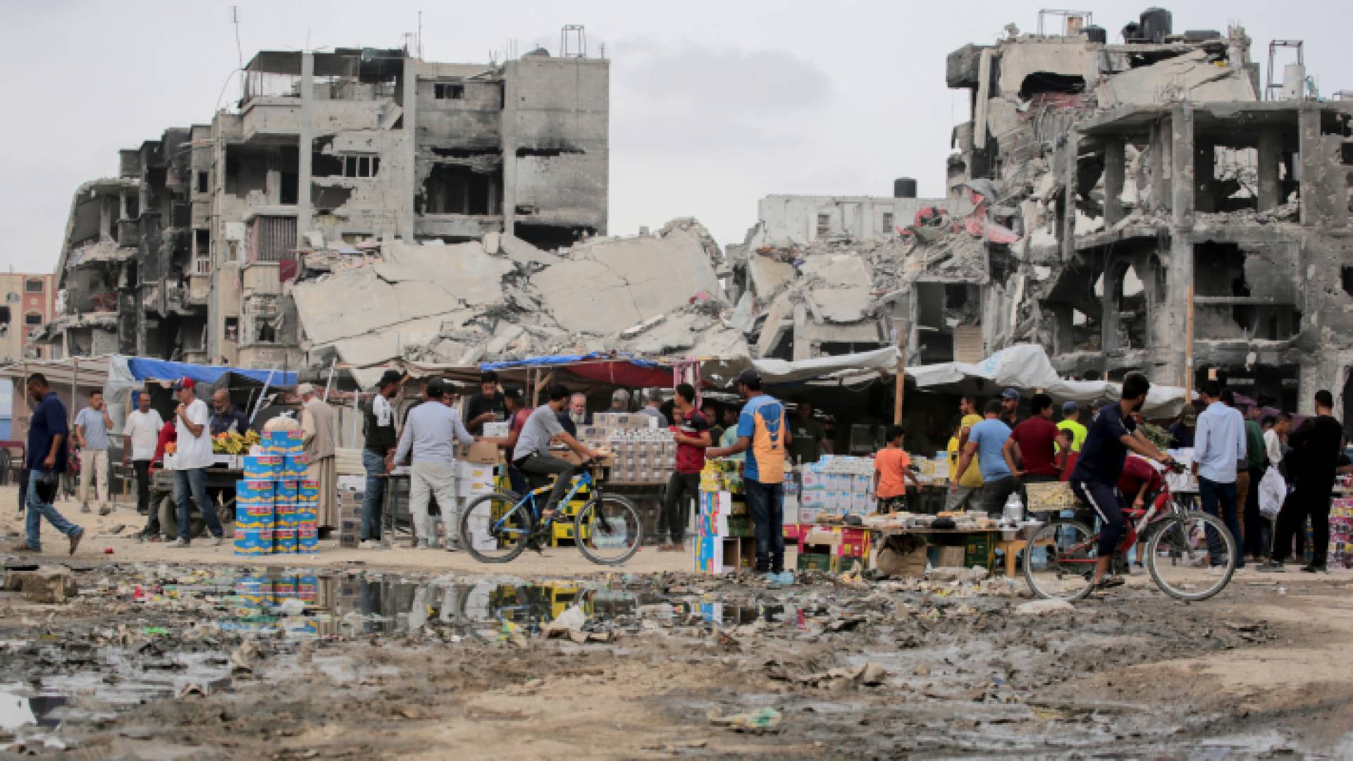 فلسطينيون يتسوقون في سوق مؤقت بالقرب من المباني المتضررة بشدة في خان يونس