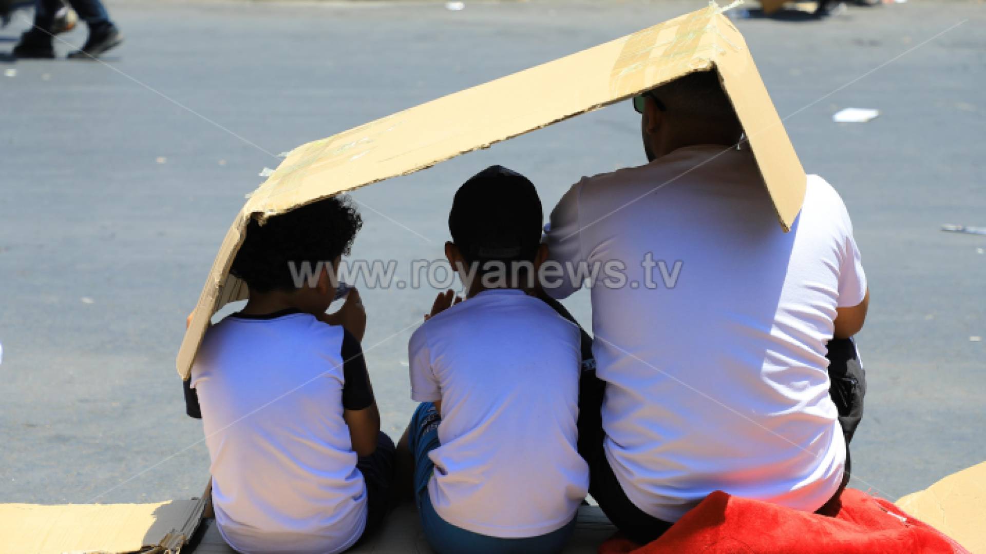 أب وأطفاله يستظلون بـ"قطعة كرتون" من أشعة الشمس في عمان