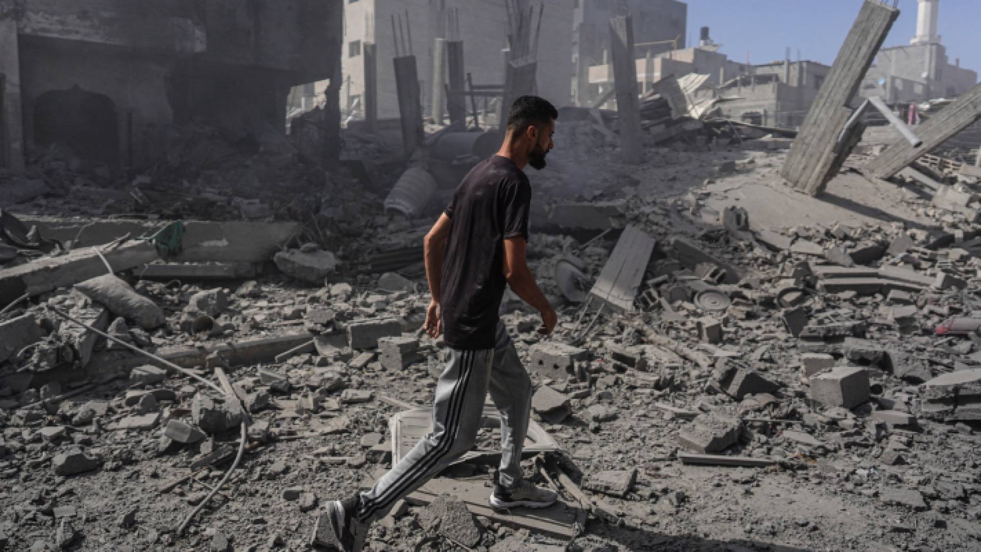 فلسطيني يقف فوق منزل دمره الاحتلال في مخيم النصيرات