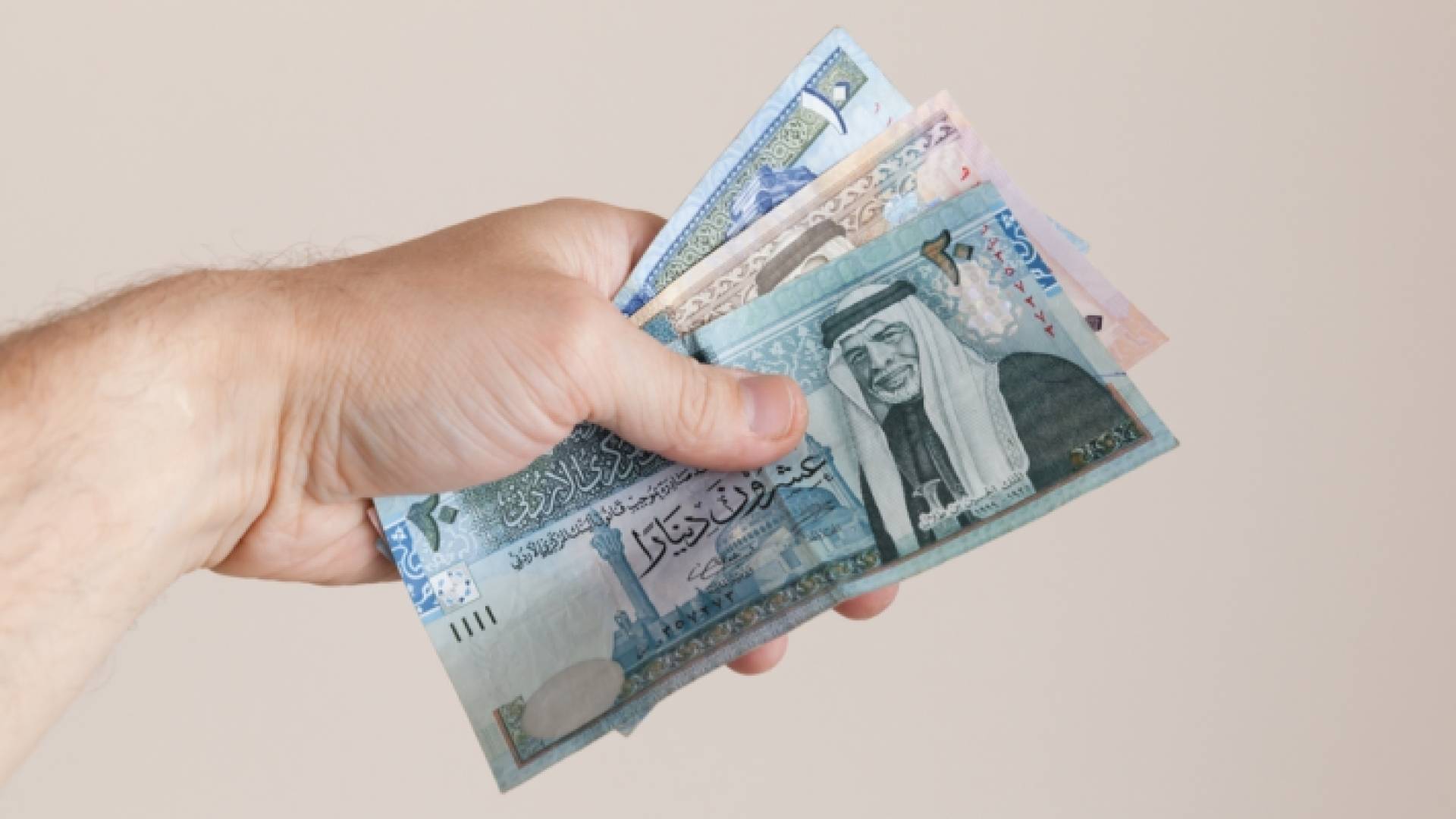 شخص يحمل عملة ورقية أردنية