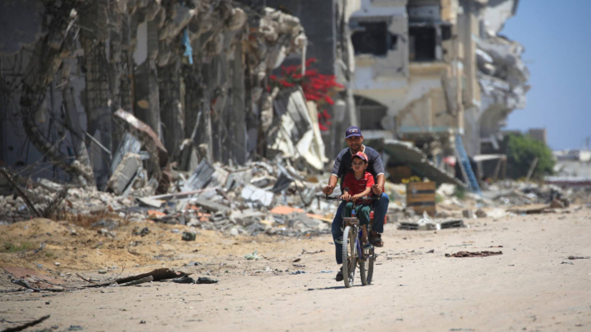 فلسطيني وطفله يمران بجانب مبان مدمرة في خان يونس