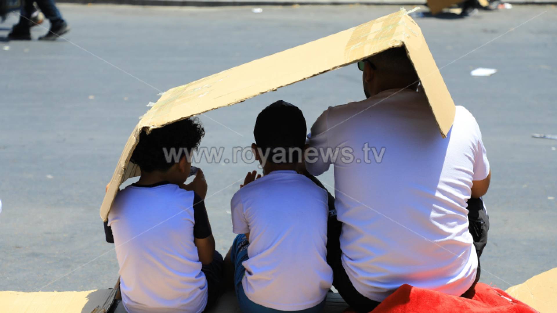 مواطن يجلس برفقة أبنائه تحت الأجواء المشمسة