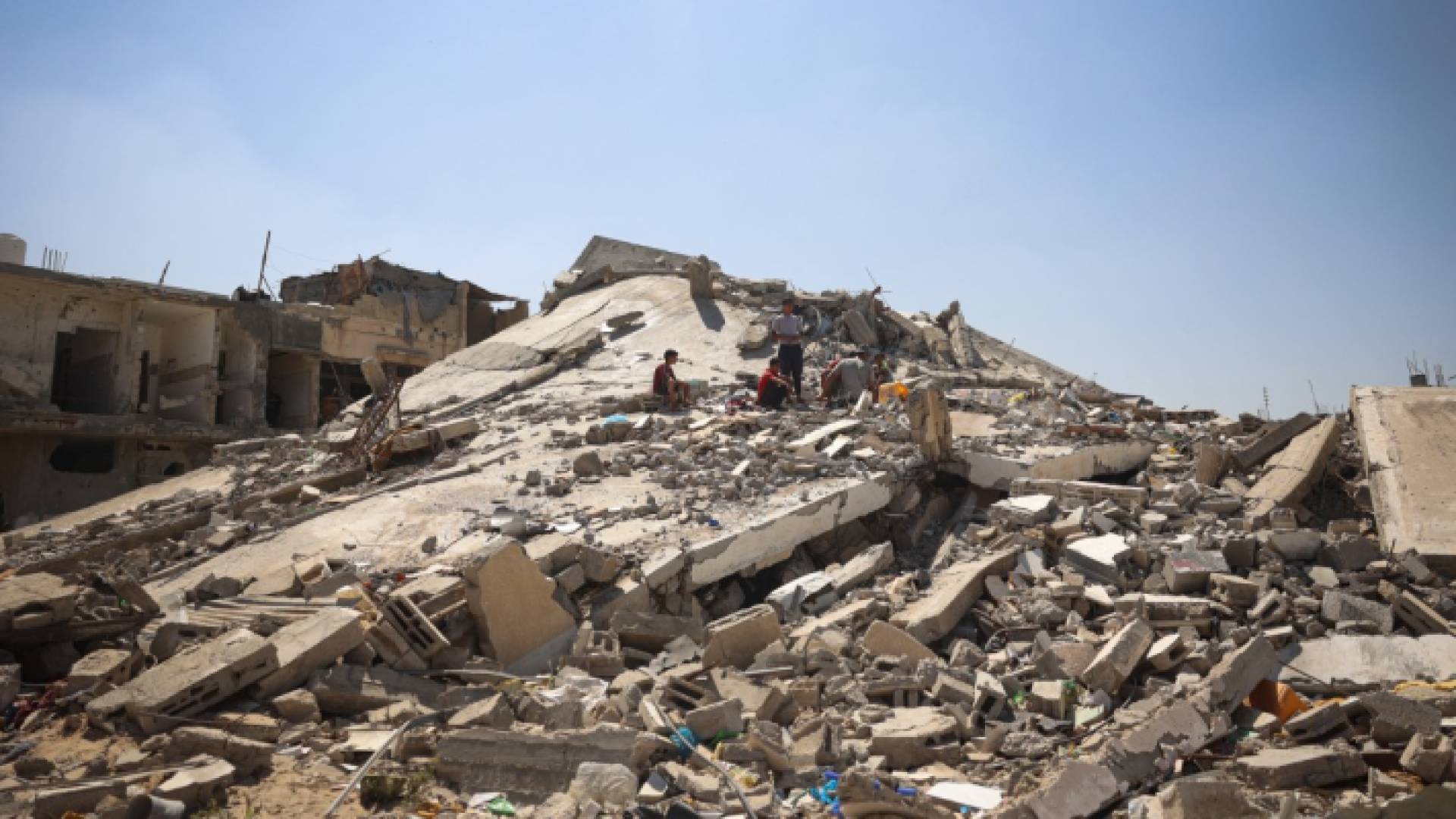 فلسطينيون يجلسون على ركام منزلهم في غزة