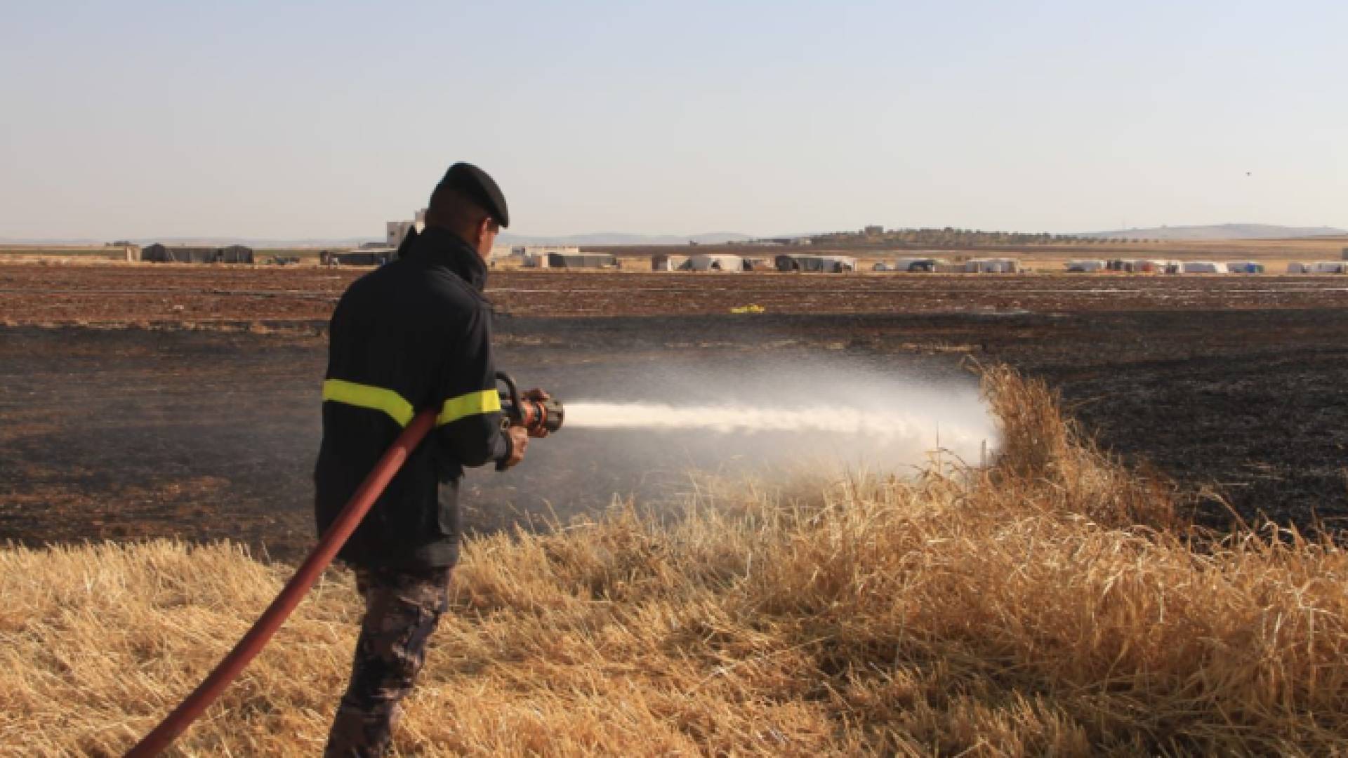 عنصر من الدفاع المدني يقوم بإخماد حريق أعشاب جافة