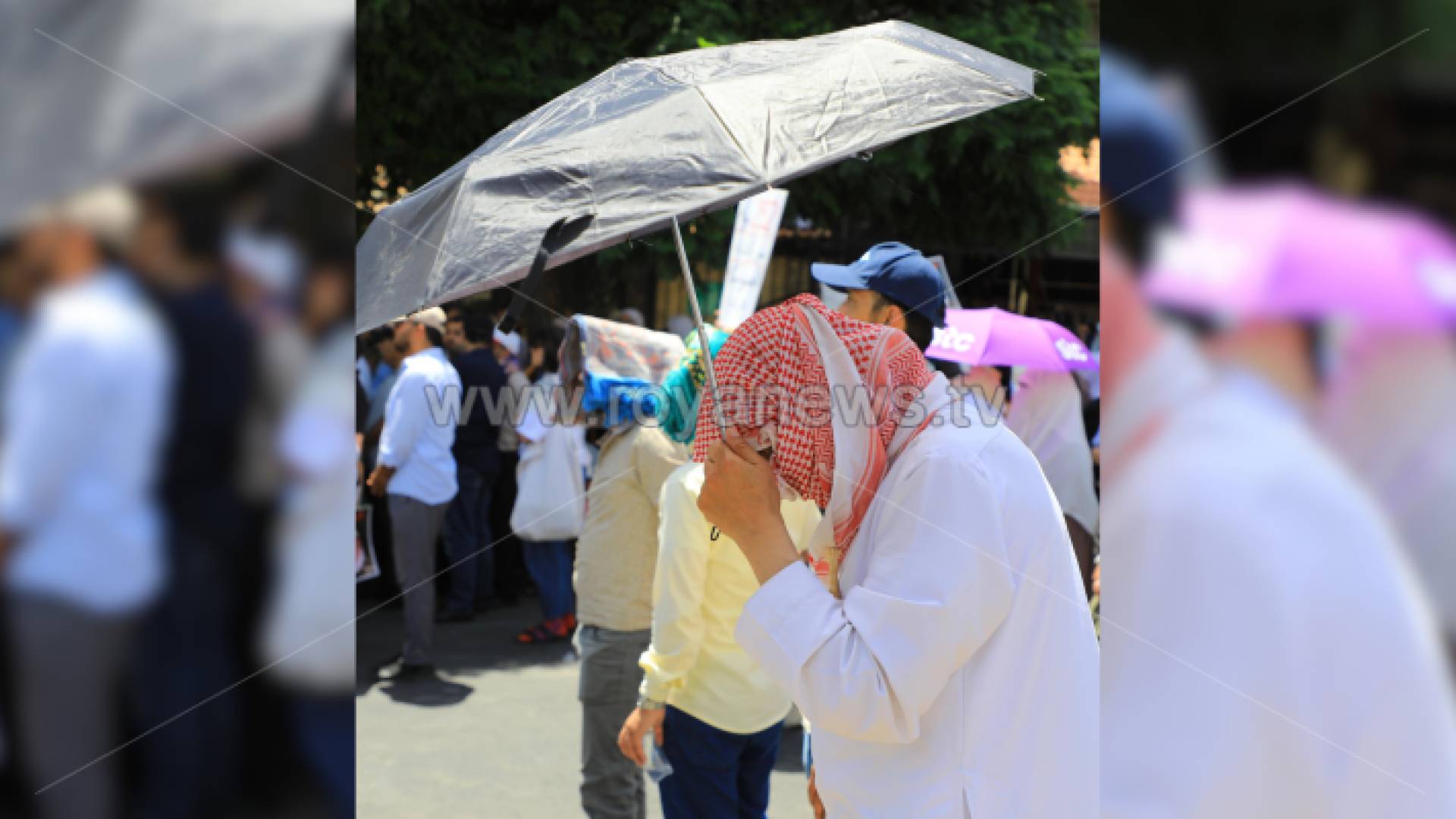 رجل يحمل مظلة للاحتماء من حرارة الشمس