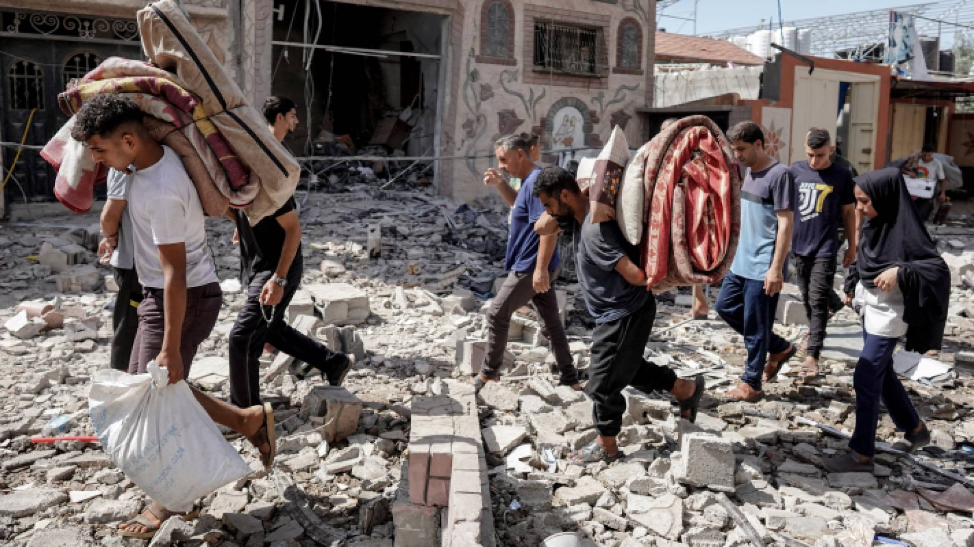 فلسطينيون يحملون أمتعتهم في مخيم النصيرات وسط قطاع غزة