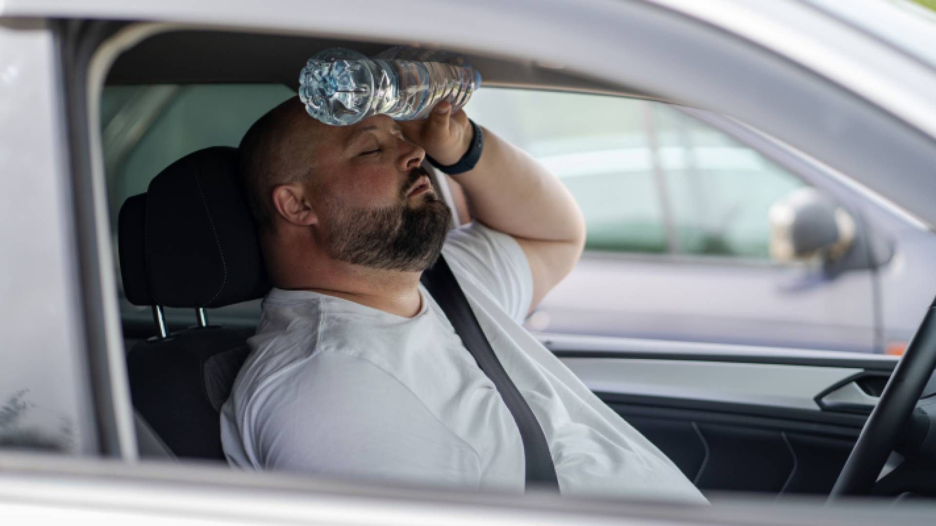 رجل يشعر بارتفاع درجات الحرارة داخل مركبته