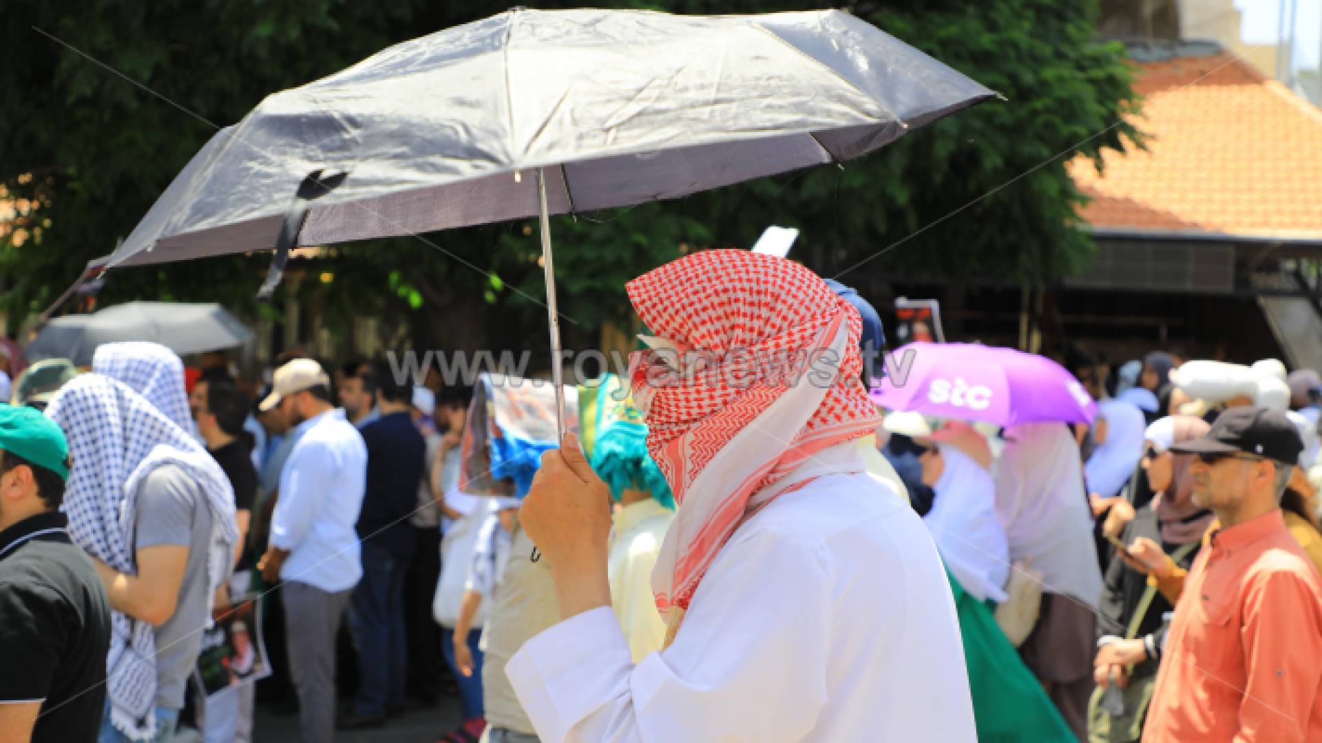 مواطن يحمل شمسية وسط الأجواء الحارة بالعاصمة عمان