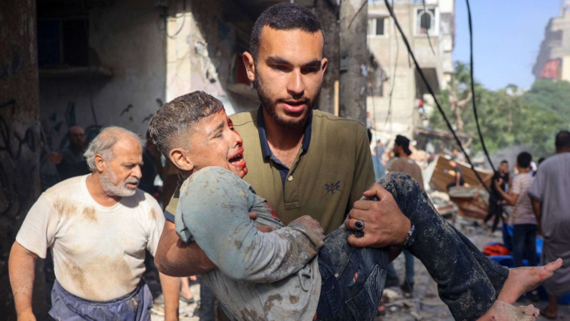 شاب فلسطيني يحمل طفل مصاب