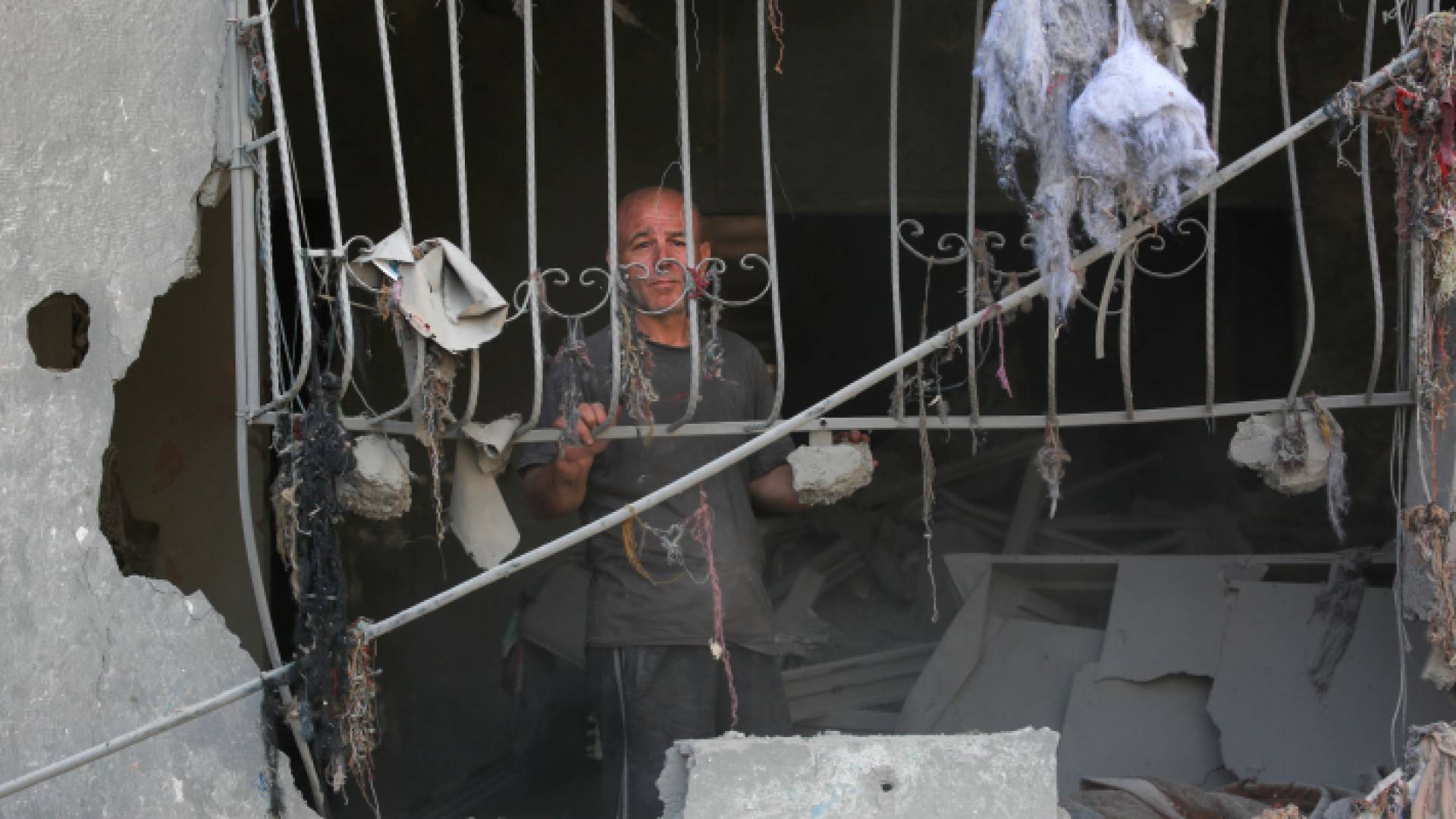 فلسطيني يقف عند نافذة منزل مدمر جراء قصف الاحتلال الإسرائيلي في مخيم البريج بقطاع غزة