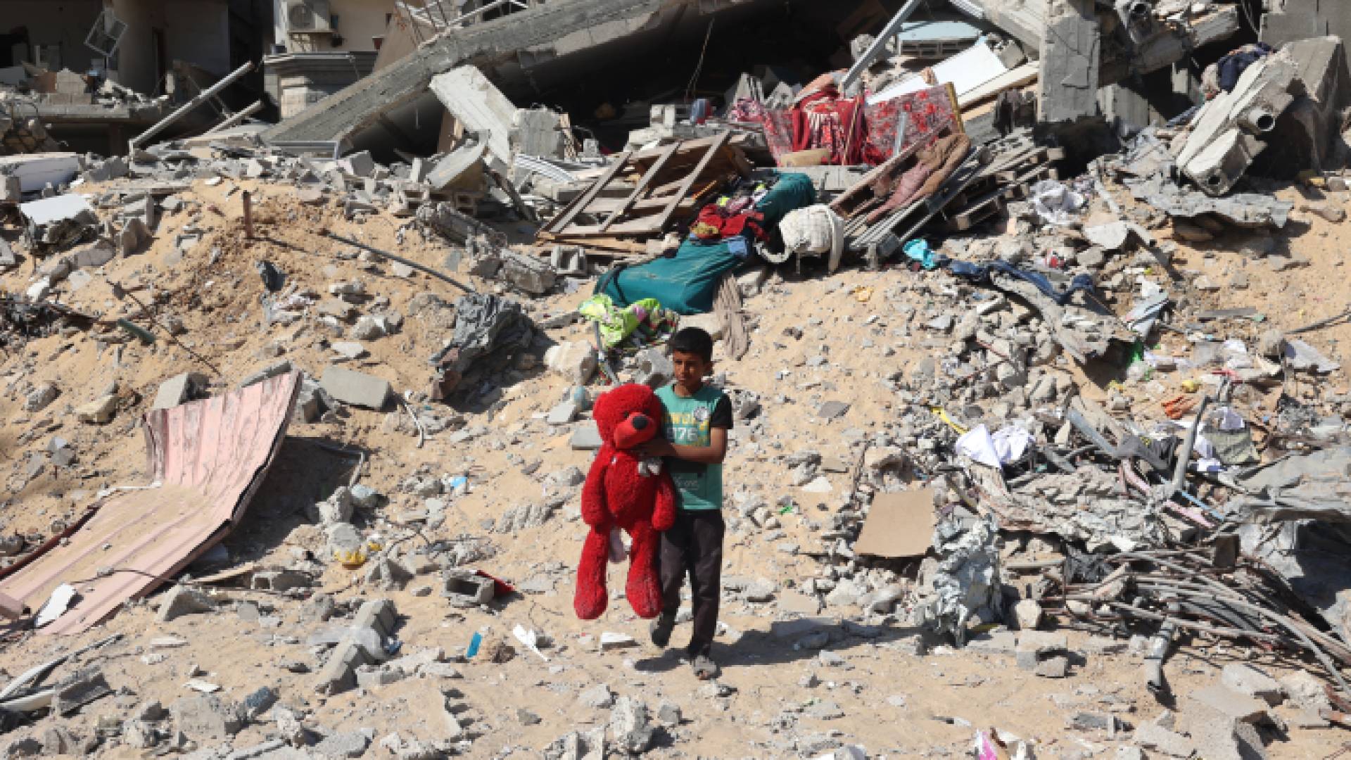 فتى فلسطيني يحمل دمية وسط الأنقاض في خان يونس جنوبي قطاع غزة