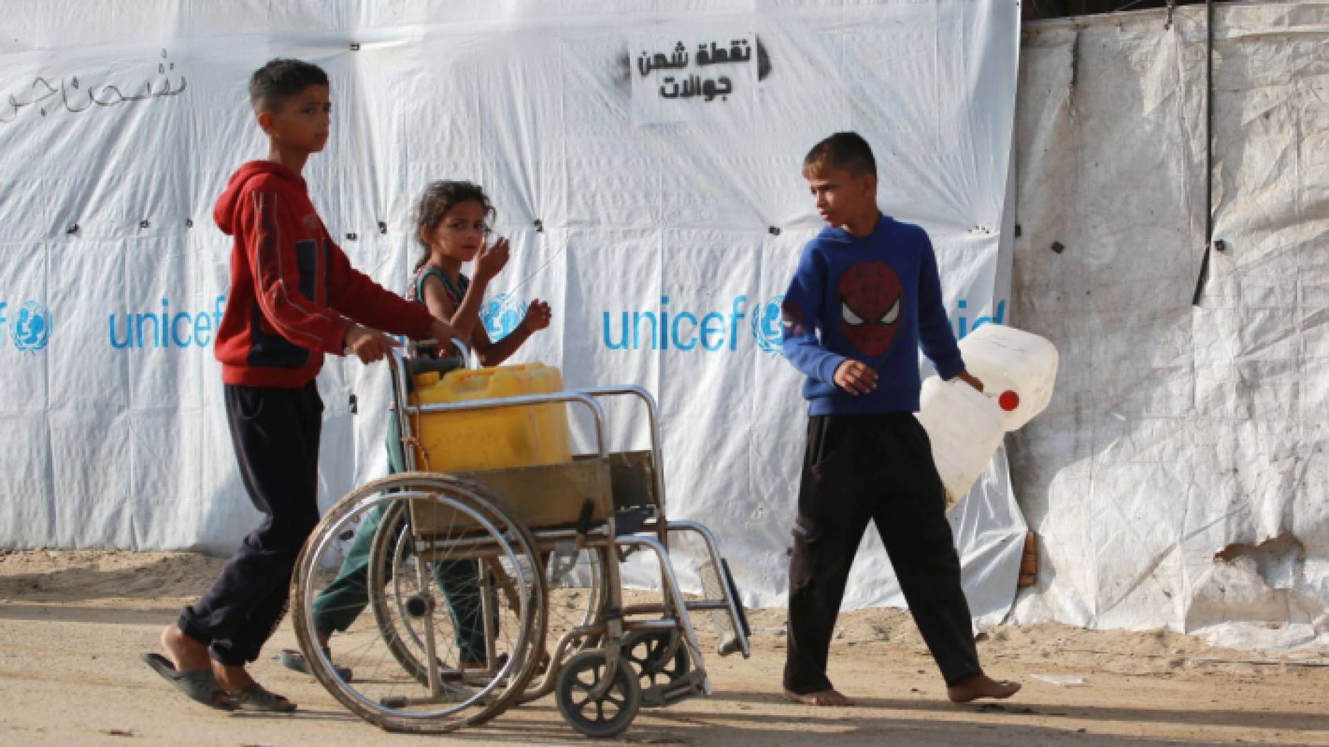 صبي يستخدم كرسيًا متحركًا لنقل المياه في مخيم للنازحين في منطقة المواصي في خان يونس جنوبd قطاع غزة