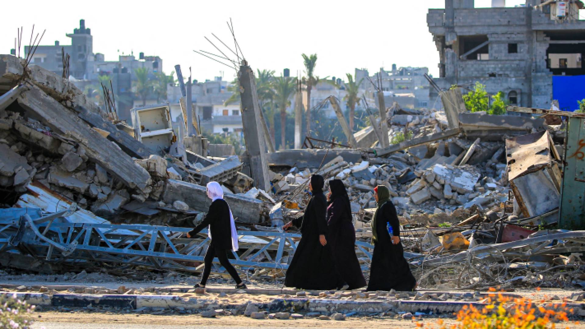 سيدات فلسطينيات بجانب المباني المدمرة جراء قصف مخيم البريج وسط غزة