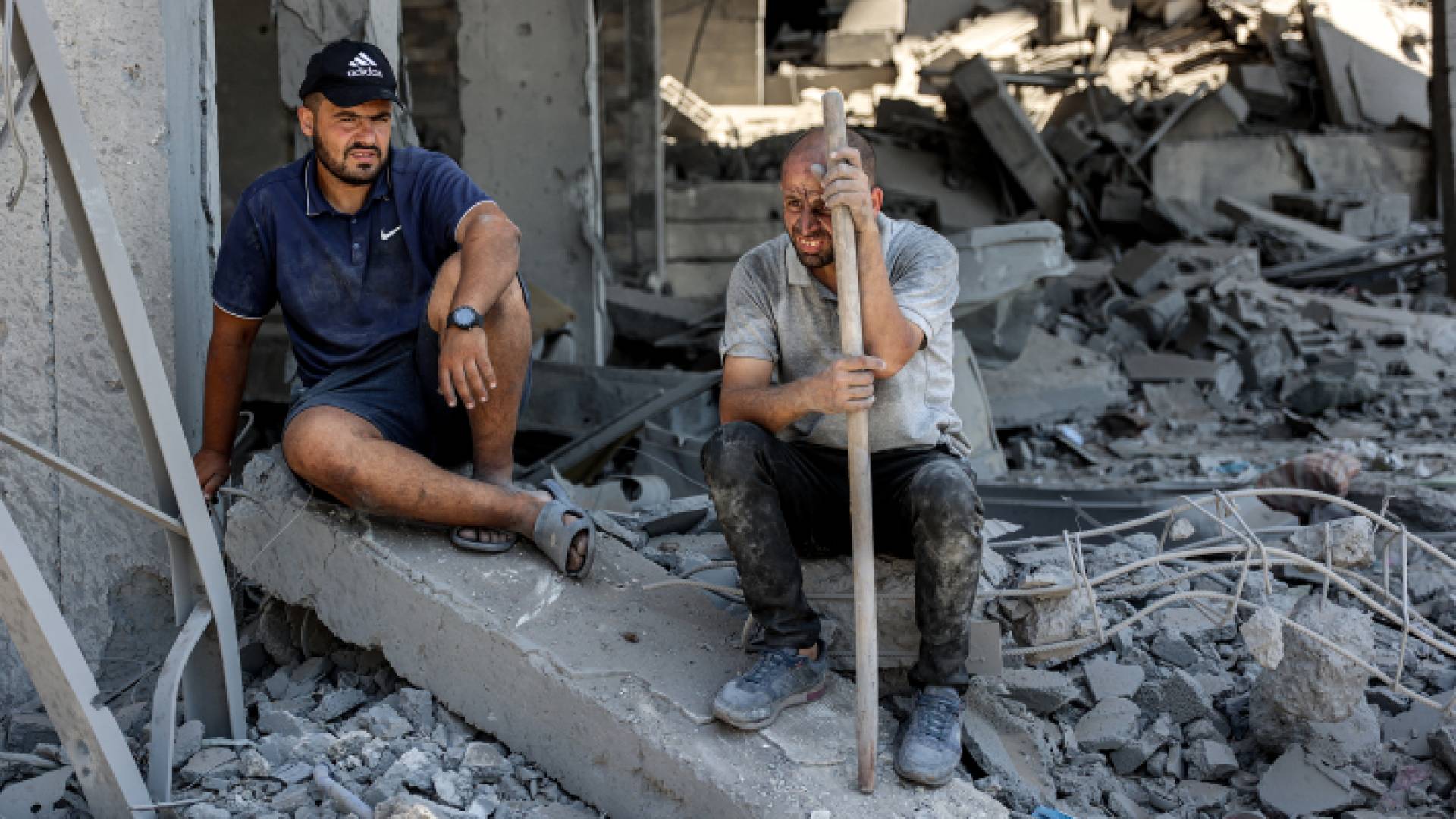 فلسطينيان يجلسان وسط الأنقاض في موقع مبنى تعرض لقصف الاحتلال في حي الصبرة جنوب مدينة غزة