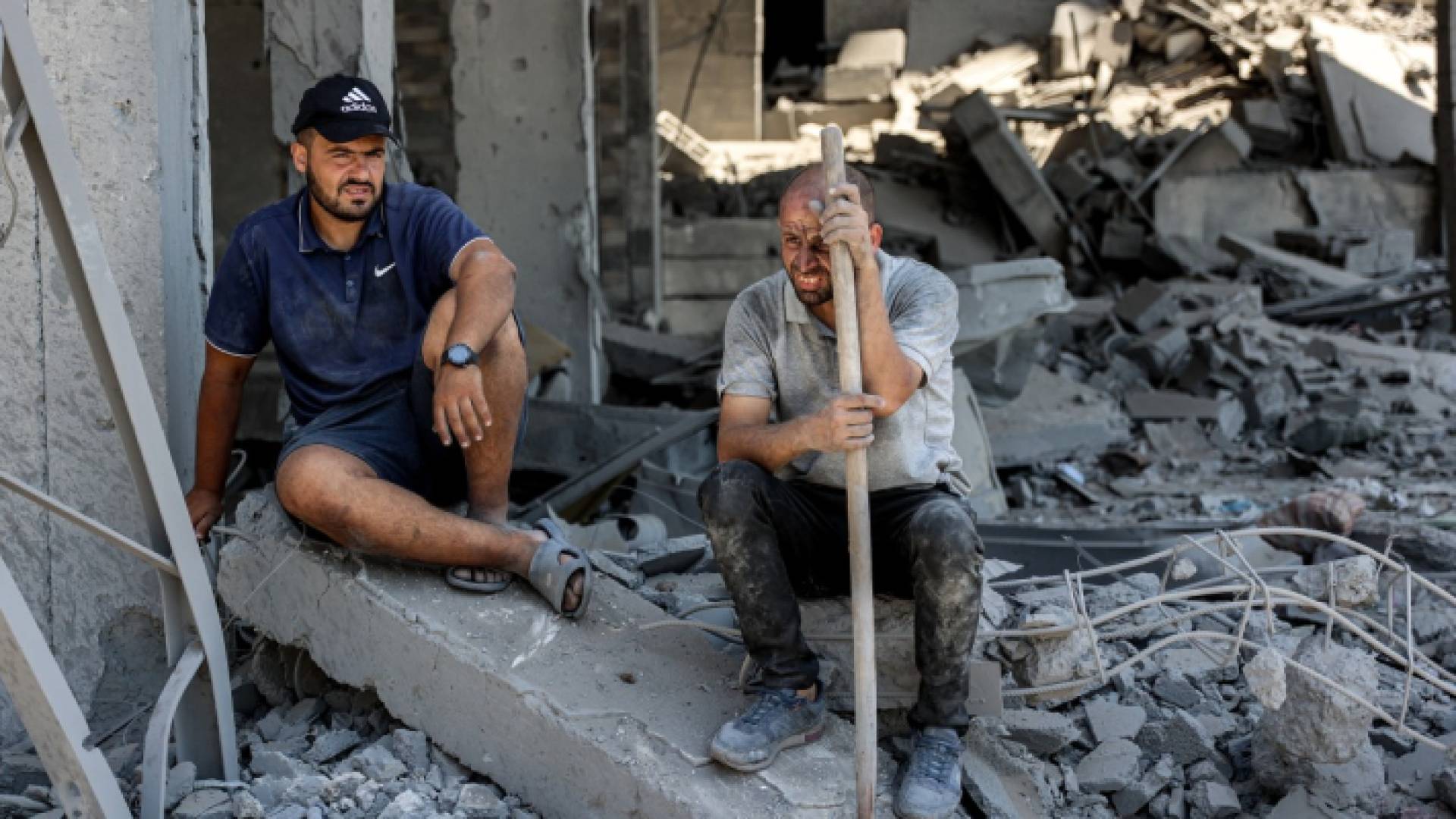 فلسطينيان يجلسان على ركام منزلهما في غزة