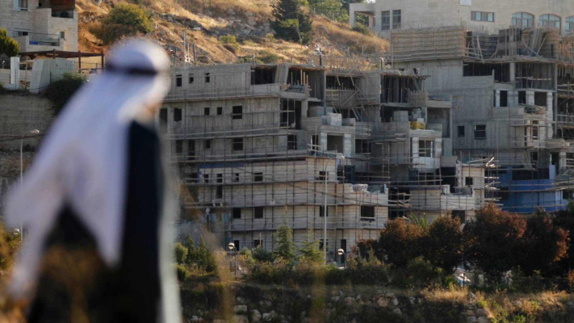 مسن فلسطيني ينظر إلى عملية بناء مستوطنات جديدة على الأرض الفلسطينية المحتلة