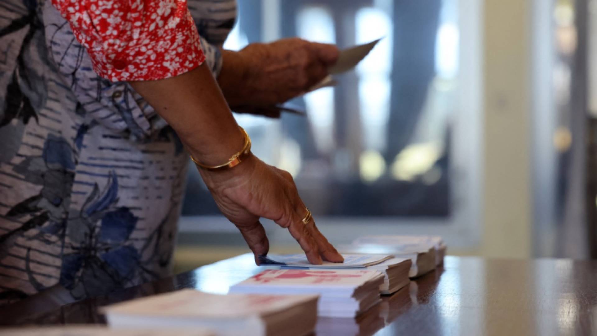 ناخب يجمع أوراق الاقتراع للتصويت في الجولة الأولى من الانتخابات البرلمانية