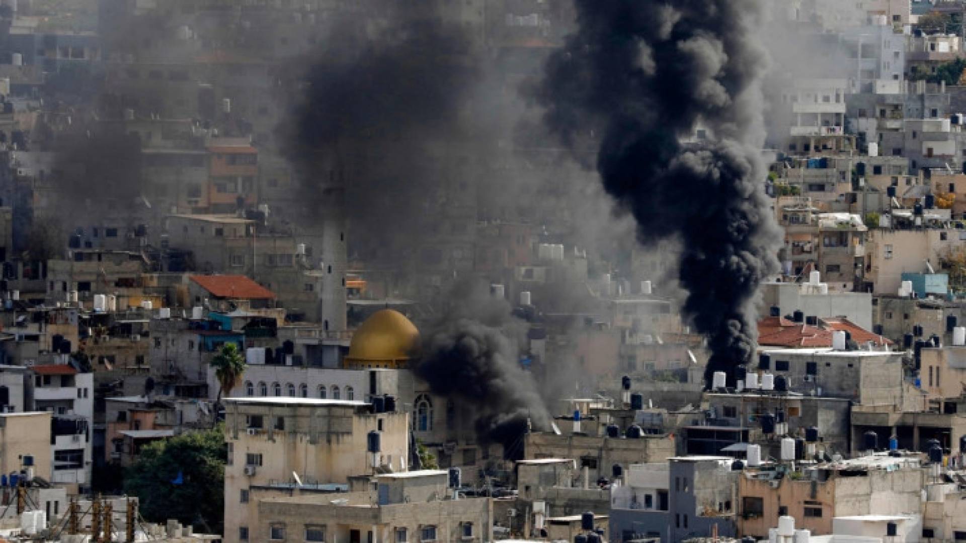 دخان يتصاعد فوق مباني في أحد مخيمات بالضفة الغربية