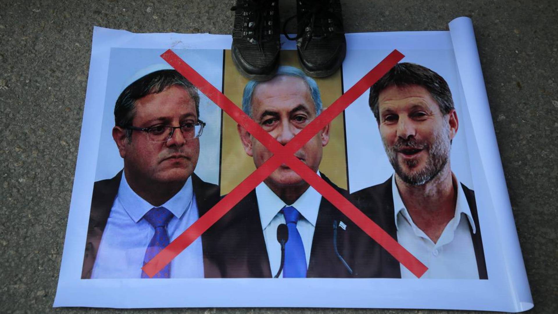 شخص يدوس على صورة مسؤولي الاحتلال المتطرفين بنيامين نتنياهو وإيتمار بن غفير وبتسلئيل سموتريتش