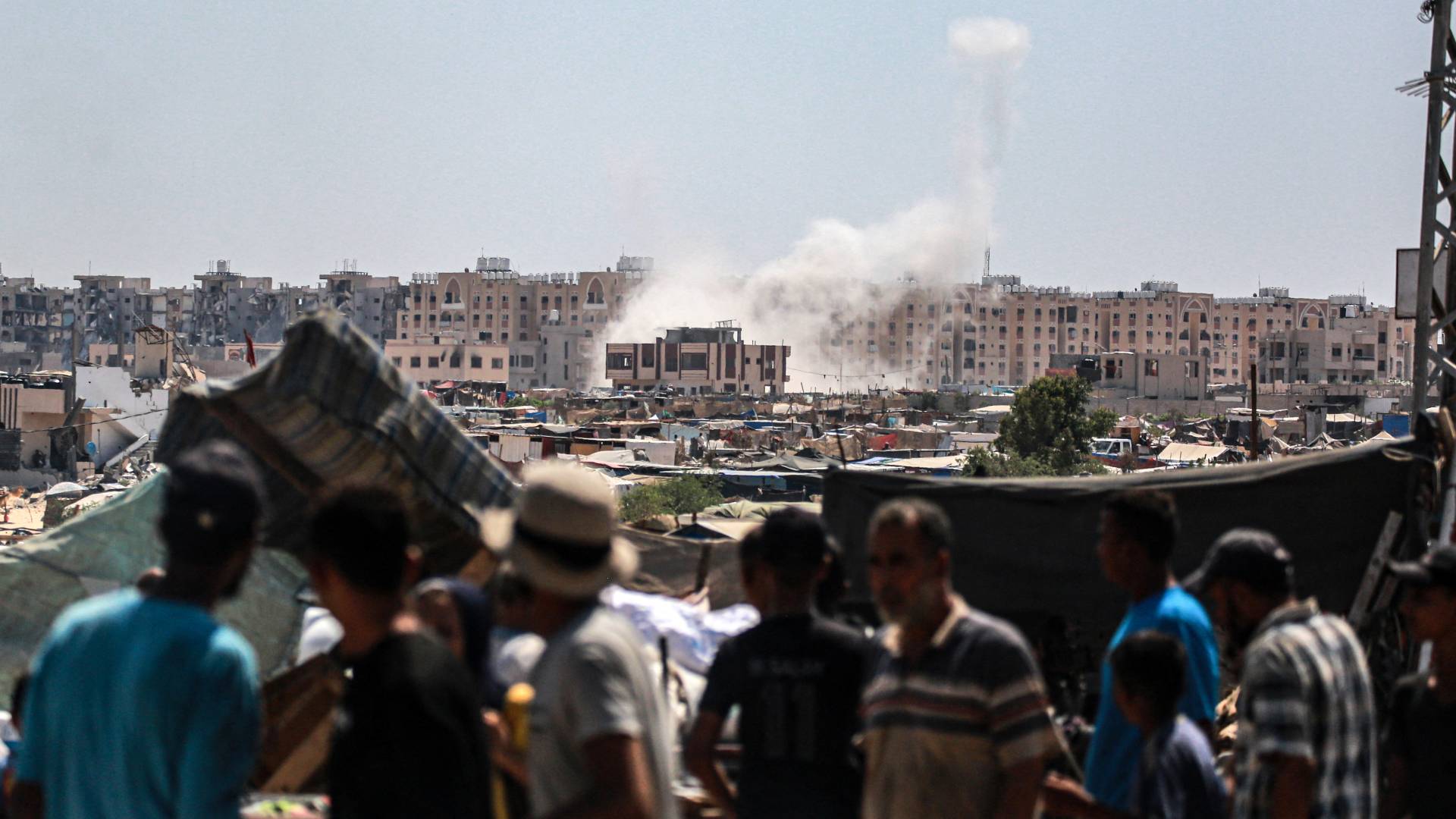 نازحون يشاهدون من مخيم بينما تسقط قذائف من دبابات الاحتلال في خان يونس