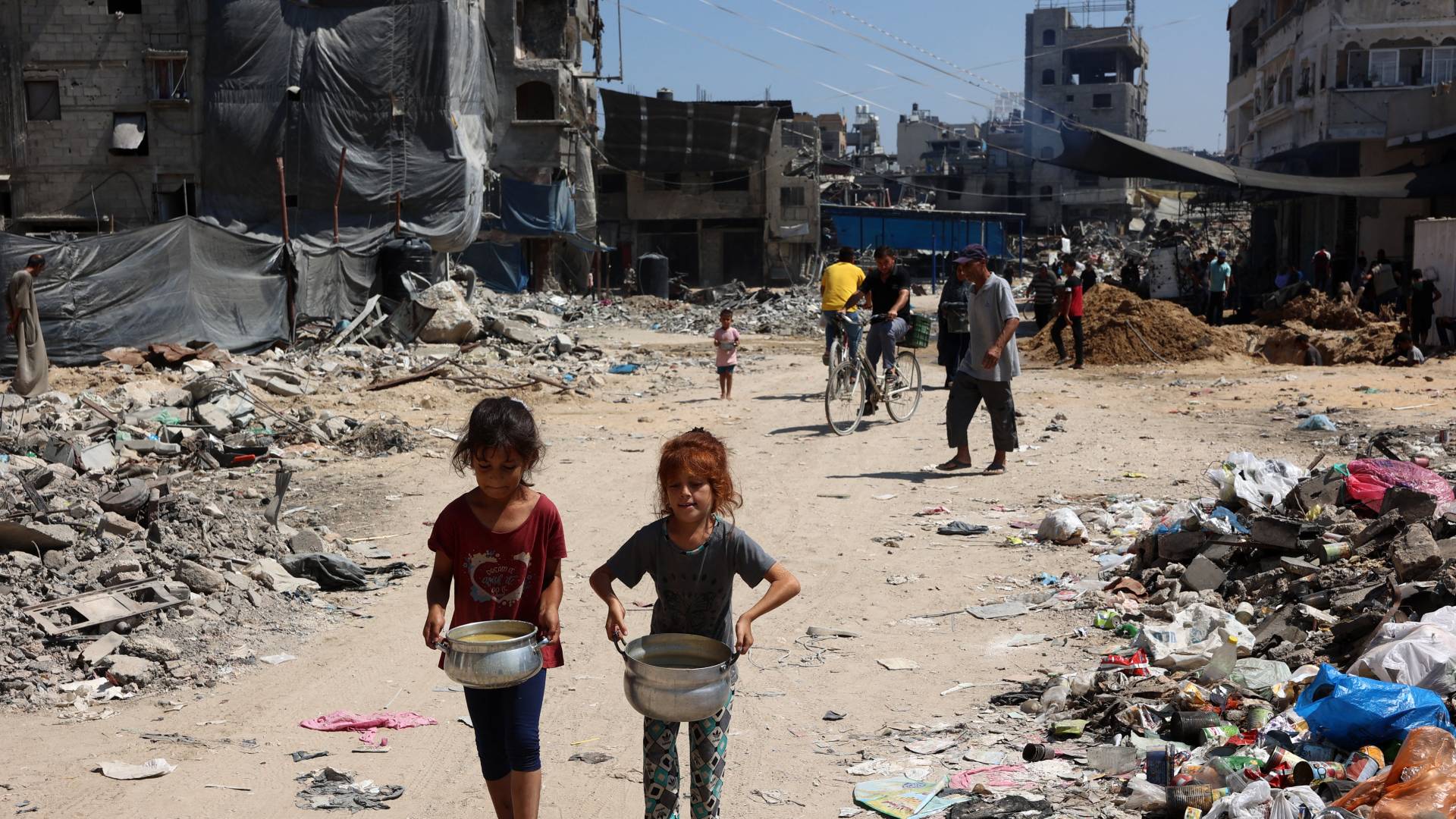 أطفال فلسطينيون يحملون أواني الحساء بالقرب من نقطة توزيع المواد الغذائية في مخيم جباليا للاجئين شمال قطاع غزة