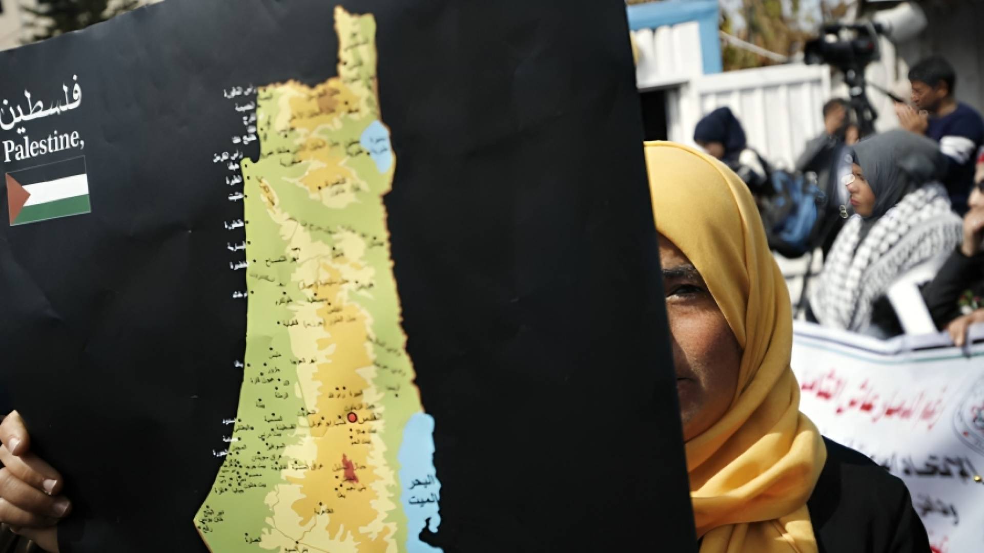 سيدة تحمل صورة لخارطة فلسطين