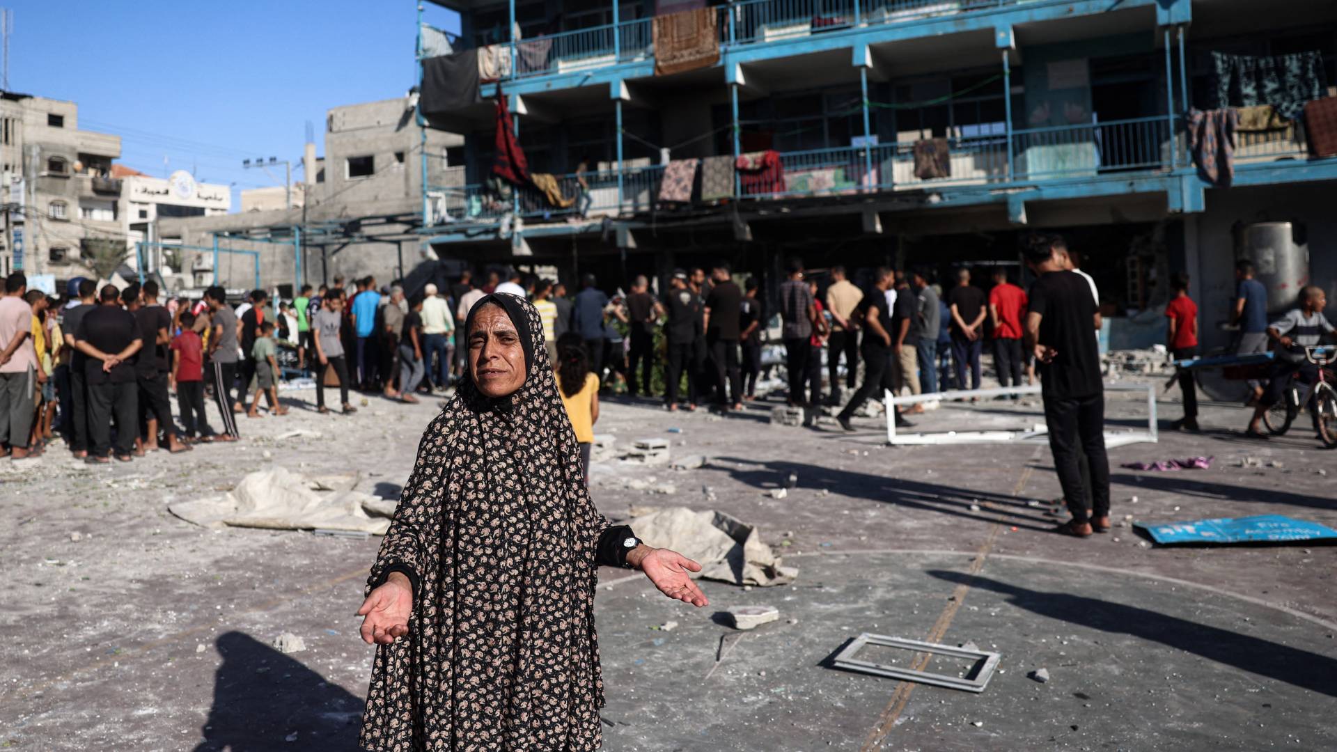 امرأة فلسطينية تشير إلى باحة مدرسة الجوني (الجاعوني) بعد غارة جوية للاحتلال بوسط قطاع غزة