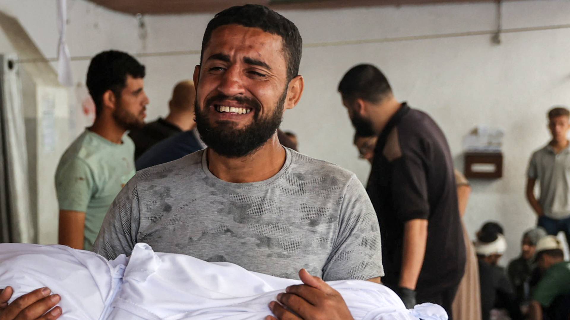 رجل يحمل طفله الشهيد جراء العدوان على غزة