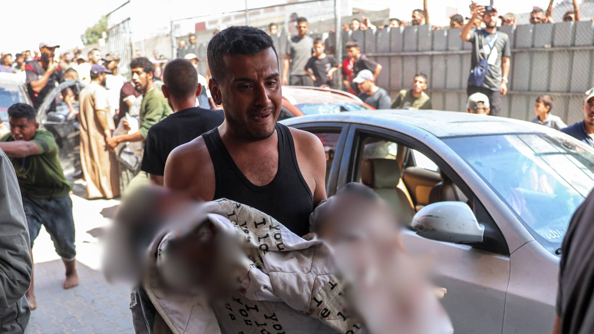 رجل يحمل فتاة مصابة بجروح خطيرة عقب استهداف مخيم في خان يونس