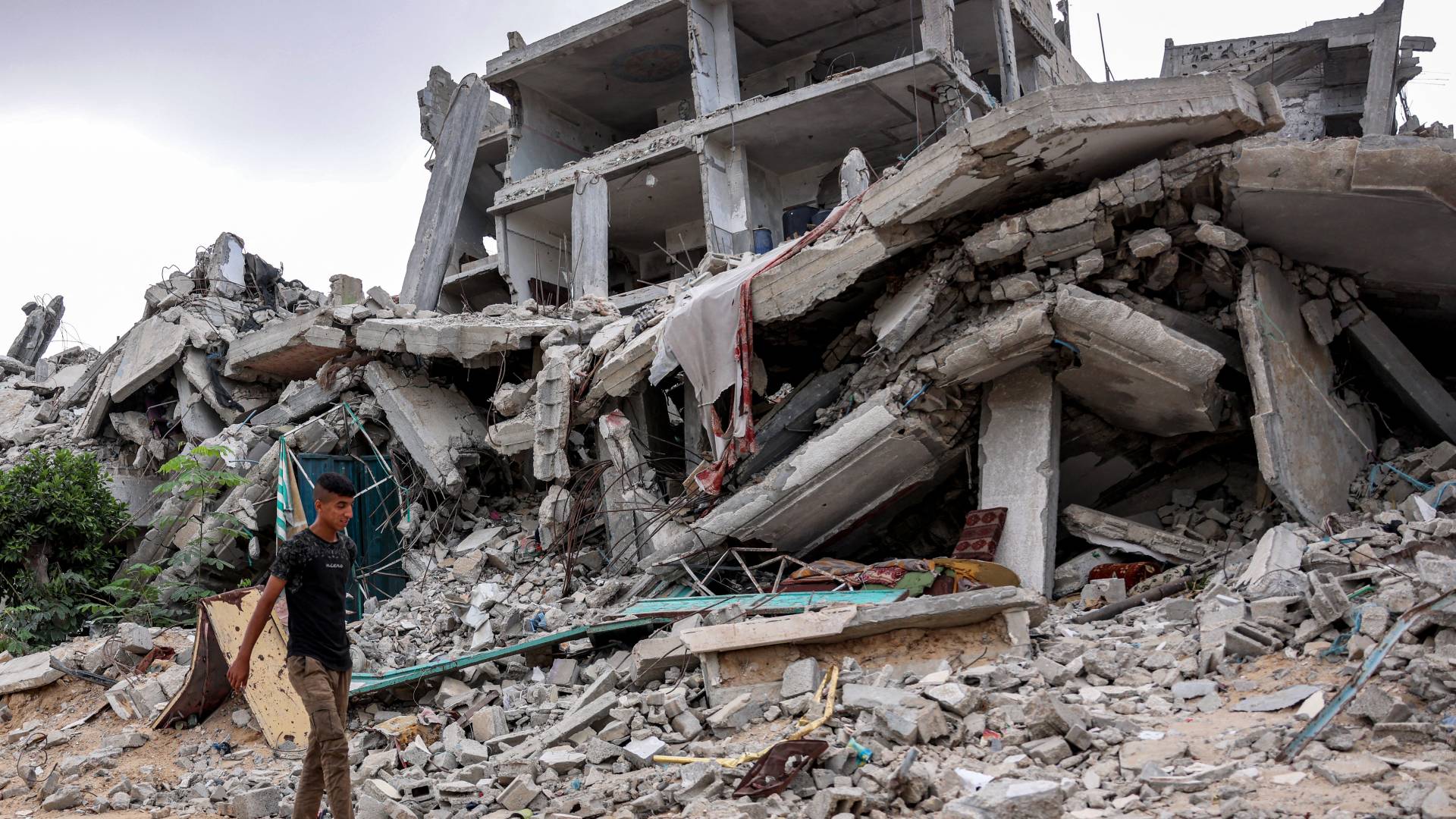رجل فلسطيني يمشي وسط مبان مدمرة بخان يونس