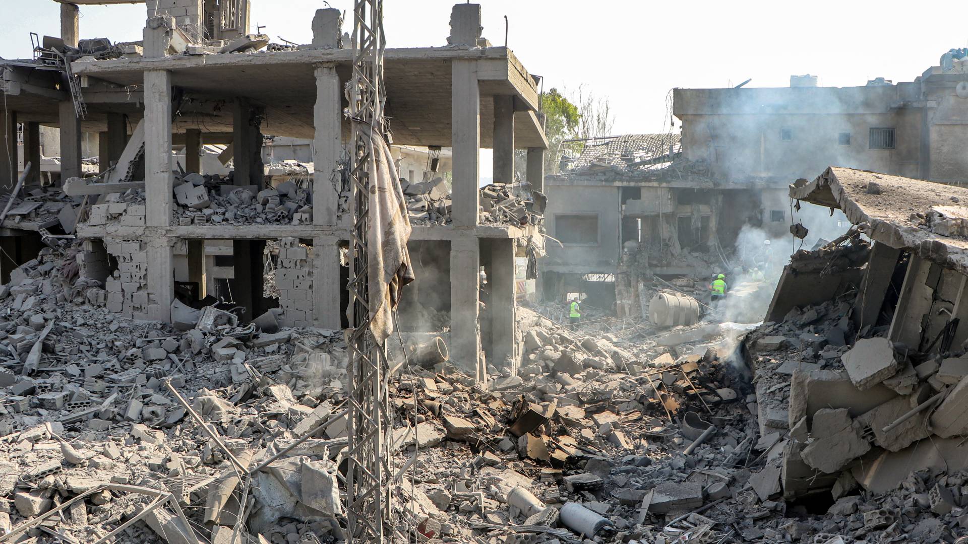 أفراد الدفاع المدني يبحثون عن ناجين بين أنقاض مبنى مدمر في موقع غارة جوية للاحتلال ليلاً على قرية قانا في جنوب لبنان