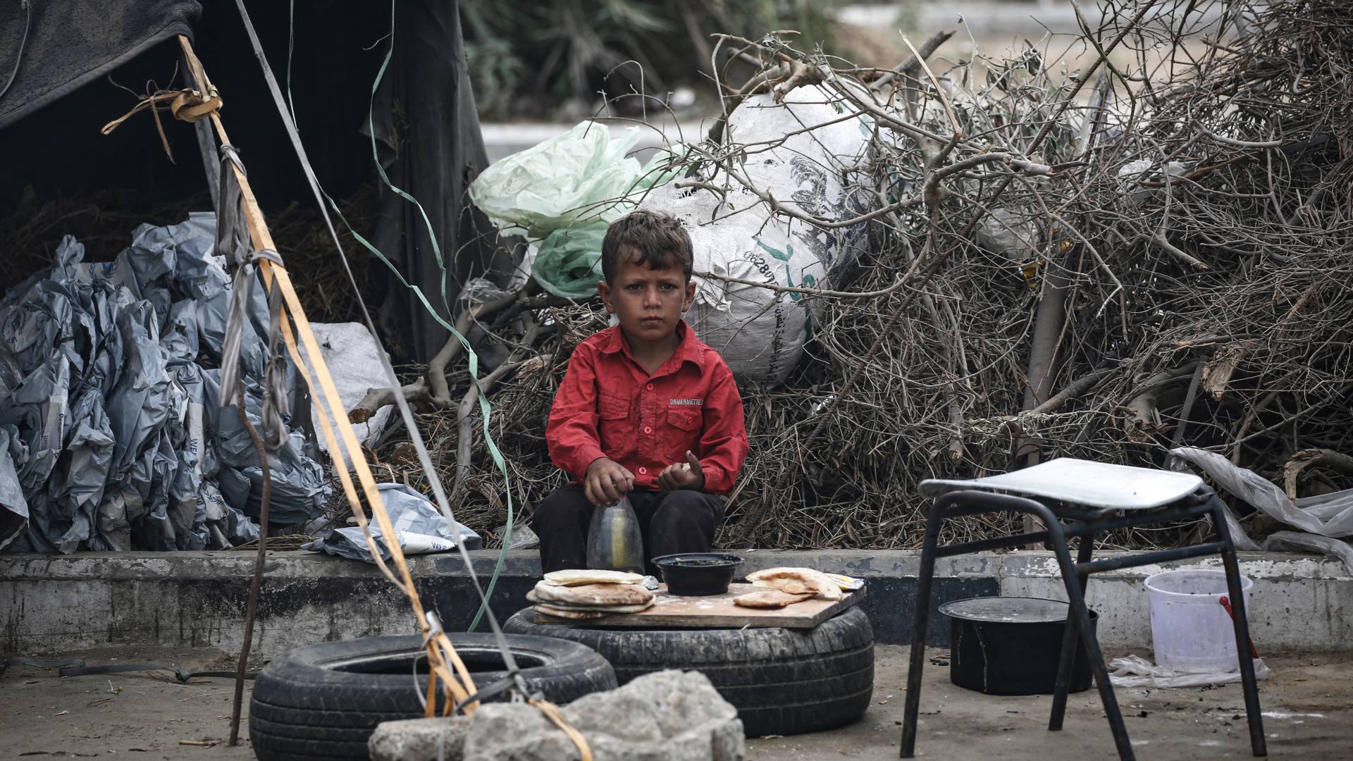 طفل فلسطيني يأكل في مخيم مؤقت للنازحين في دير البلح وسط قطاع غزة