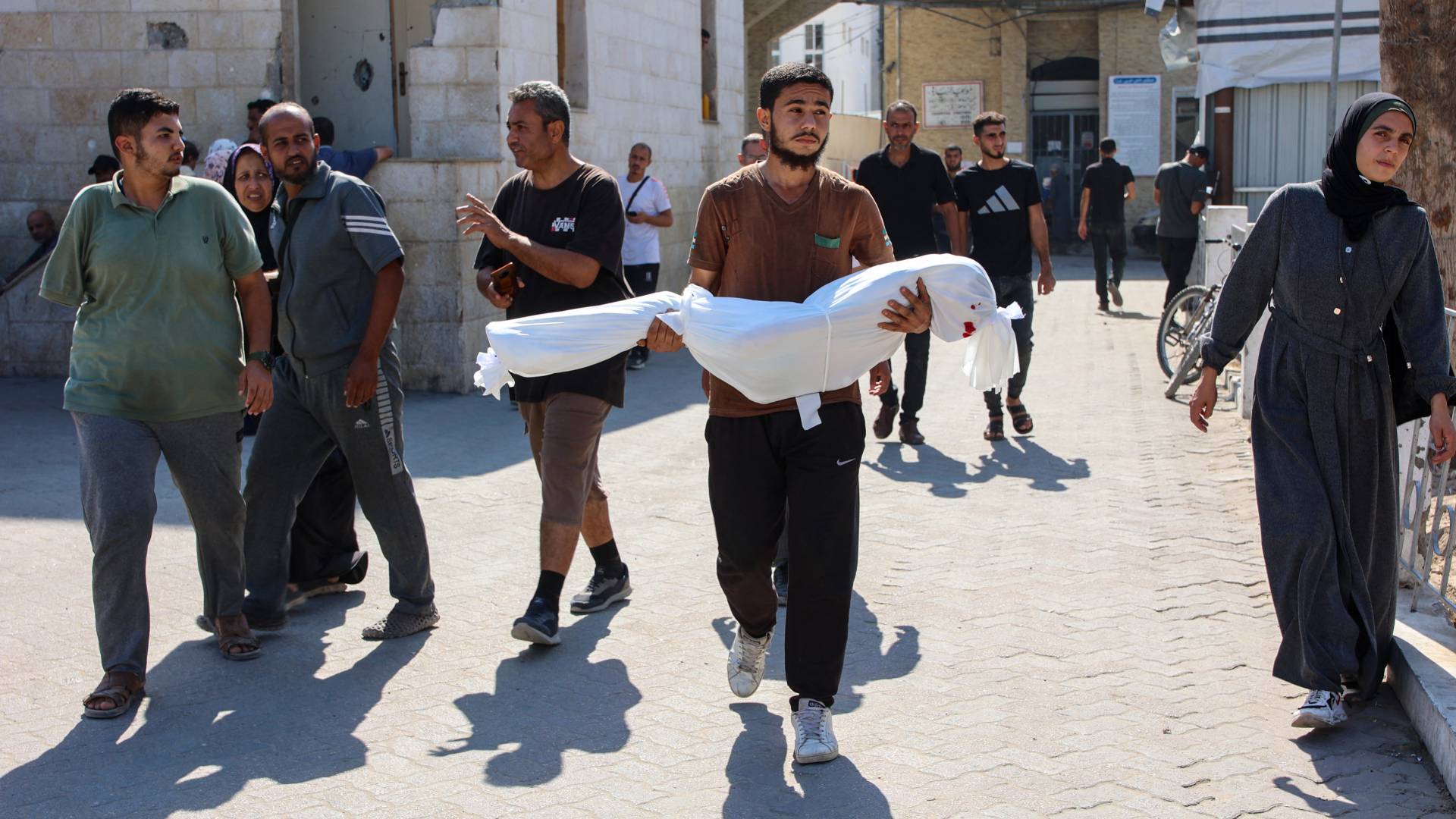 فلسطيني يحمل نجله الشهيد في غزة