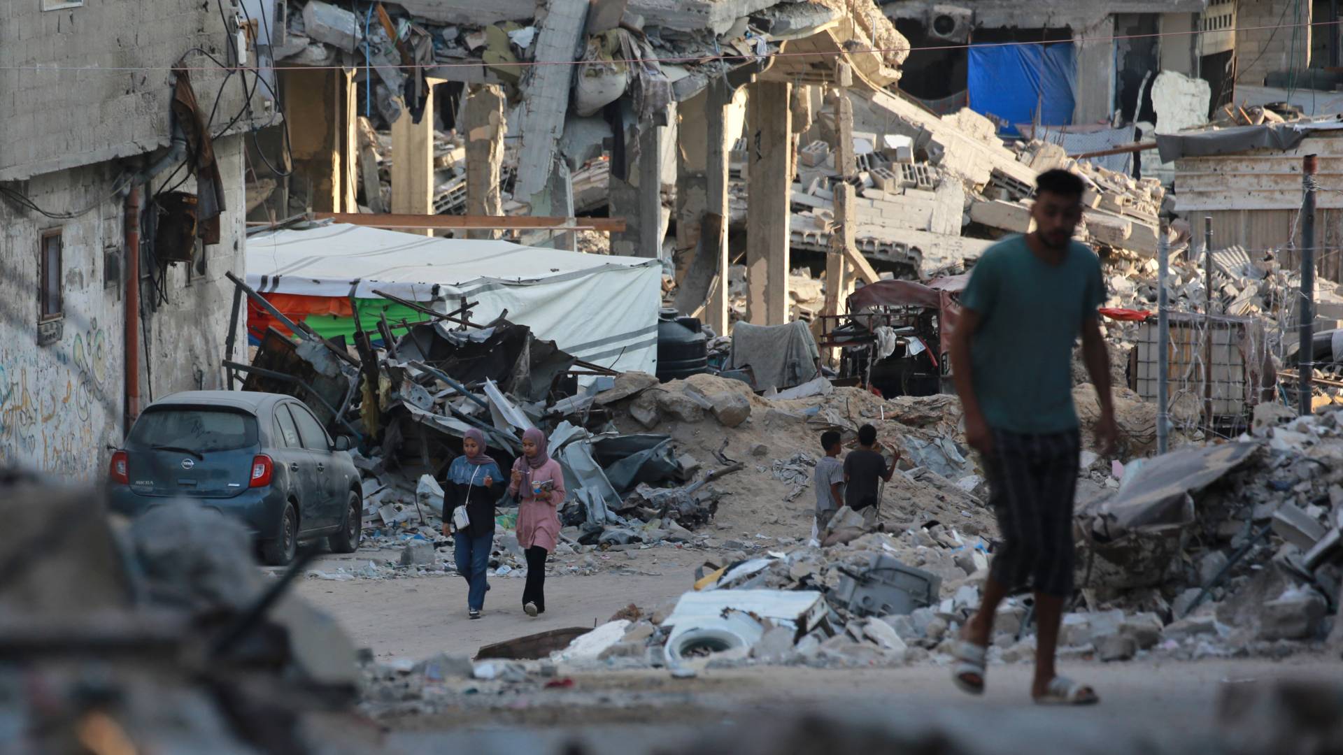 فلسطينيون يمرون بجوار مبان مدمرة في خان يونس جنوب قطاع غزة