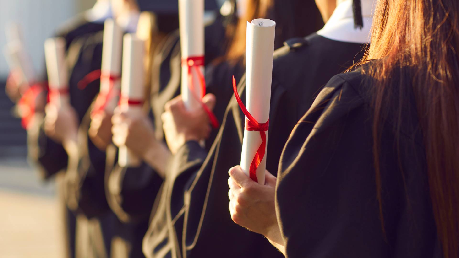 صورة تظهر طلبة يحملون شهادات ثانوية عامة