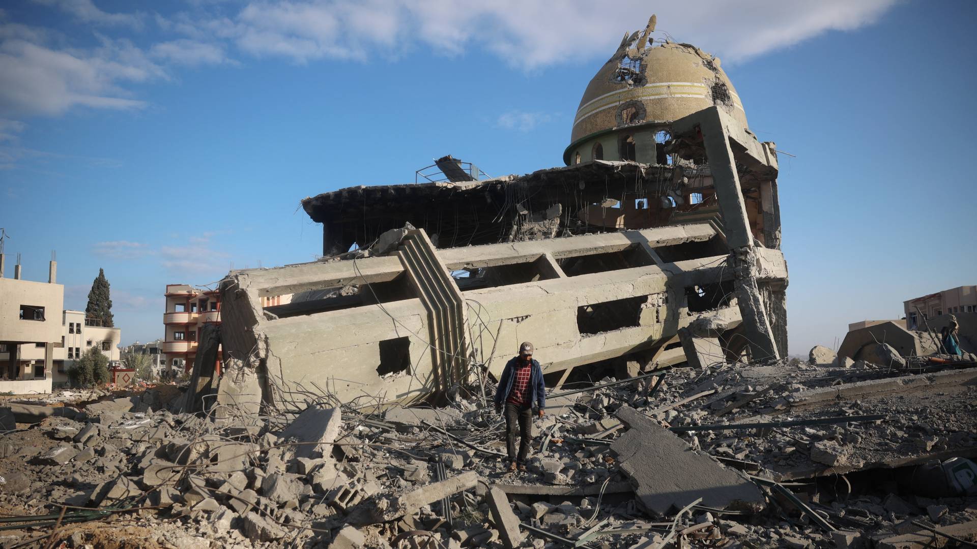 رجل فلسطيني يسير وسط الأنقاض أمام مسجد مدمر في النصيرات وسط قطاع غزة
