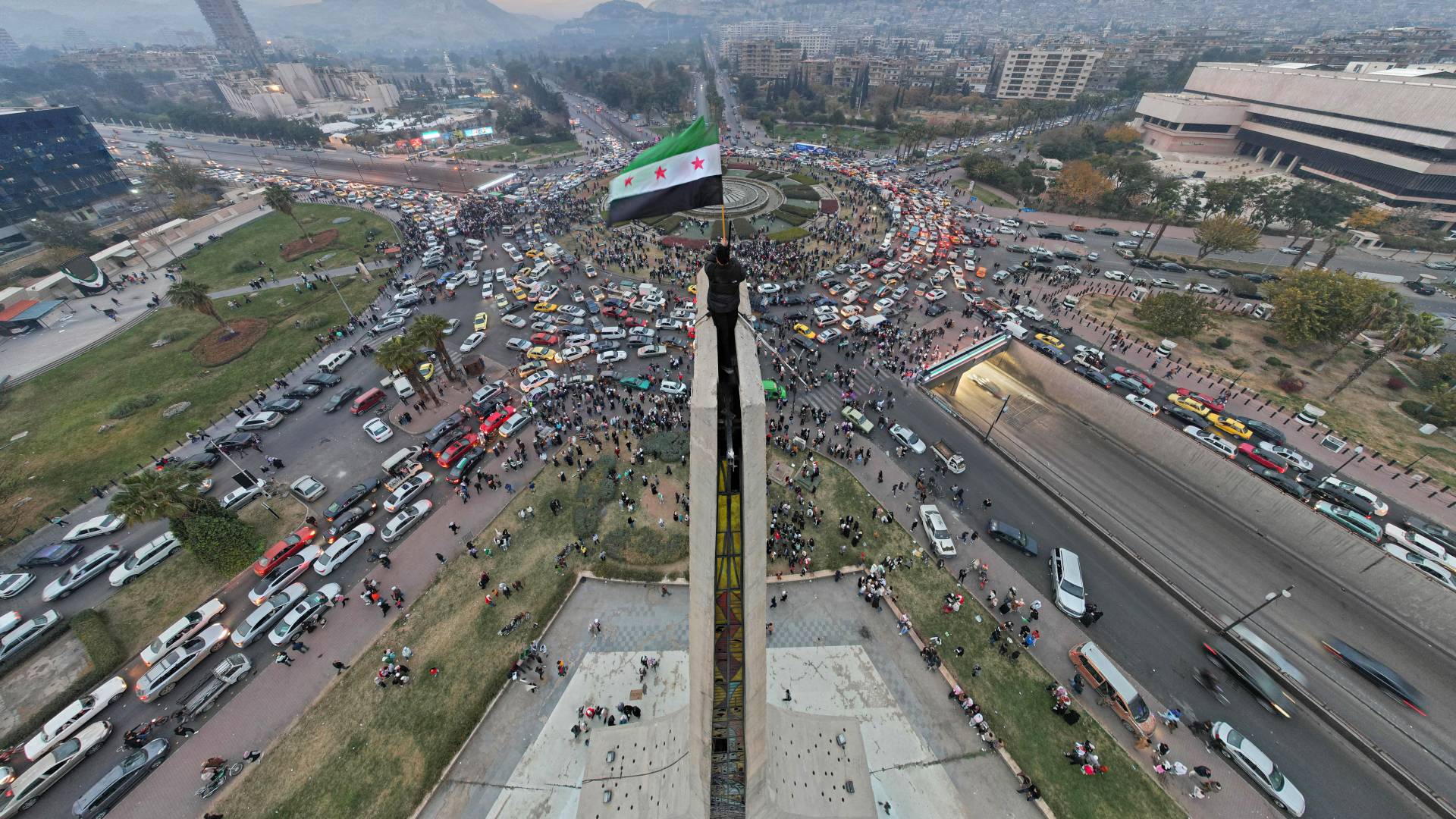منظر جوي يظهر رجلاً سورياً يلوح بالعلم السوري في عصر الاستقلال في ساحة الأمويين بوسط دمشق