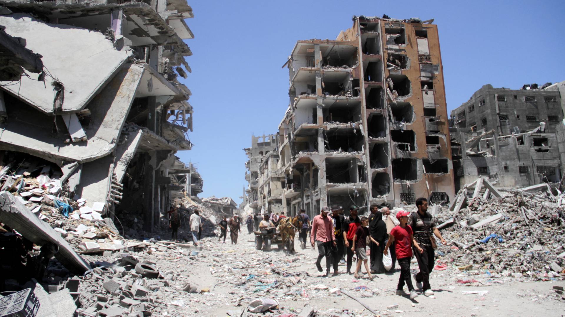 فلسطينيون يسيرون بين أنقاض المنازل في جباليا